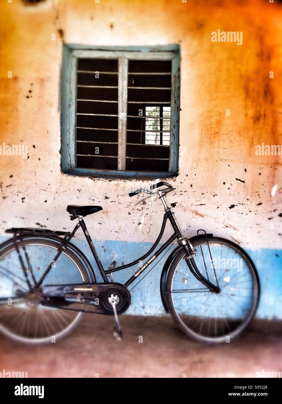 Bicicletta appoggiata sul muro nel villaggio rurale in India. Foto Stock