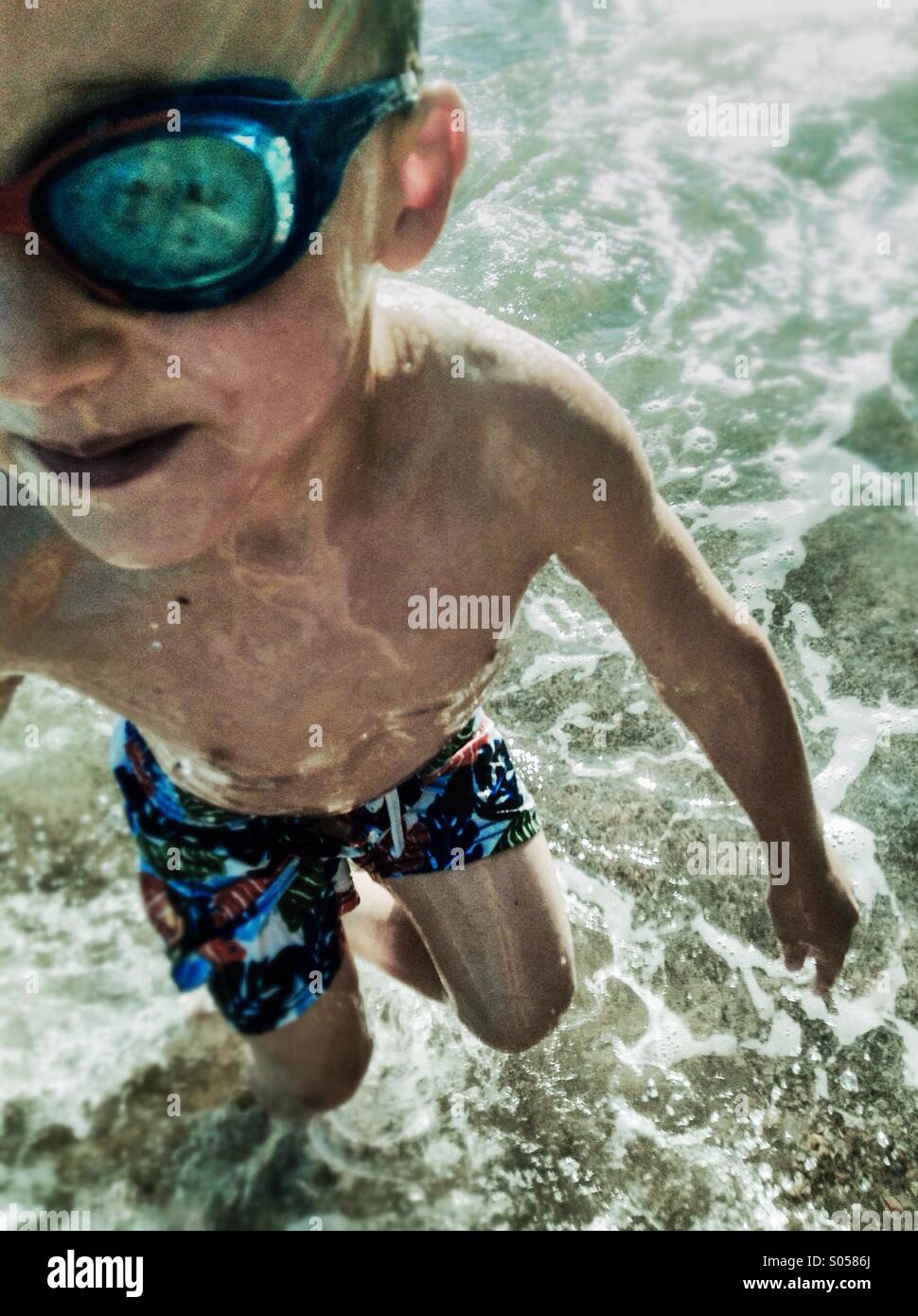 Un ragazzo correre e giocare in onde su Sant Pol de Mar spiaggia. Mare Mediterraneo, el Costa Maresme, Barcellona, Spagna Foto Stock