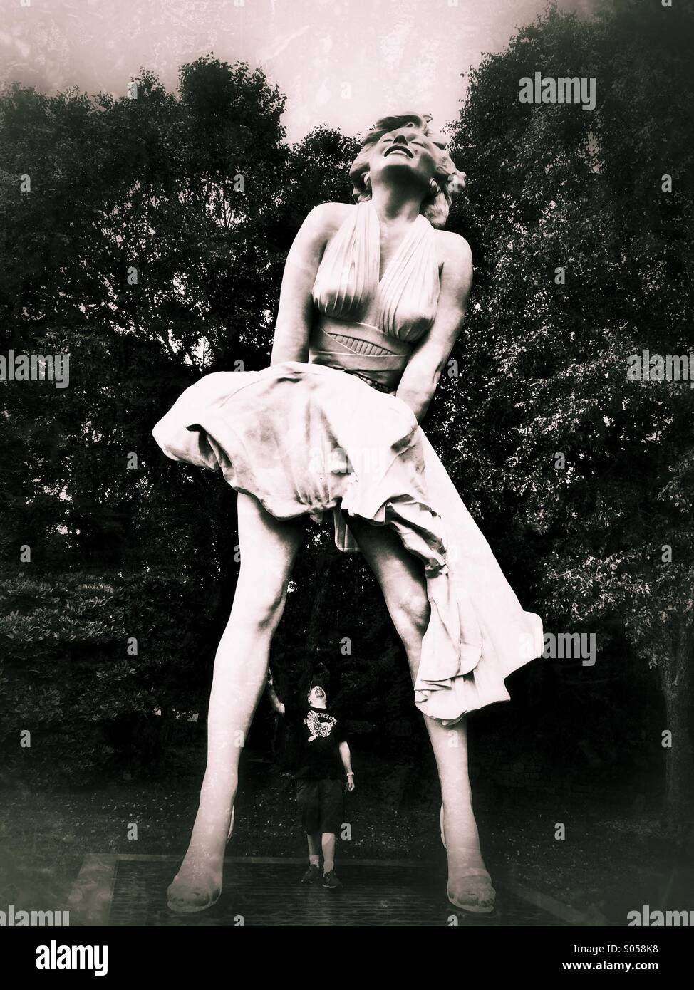 Uomo in piedi al di sotto di Marilyn Monroe Scultura e cercando fino sotto il suo vestito Foto Stock