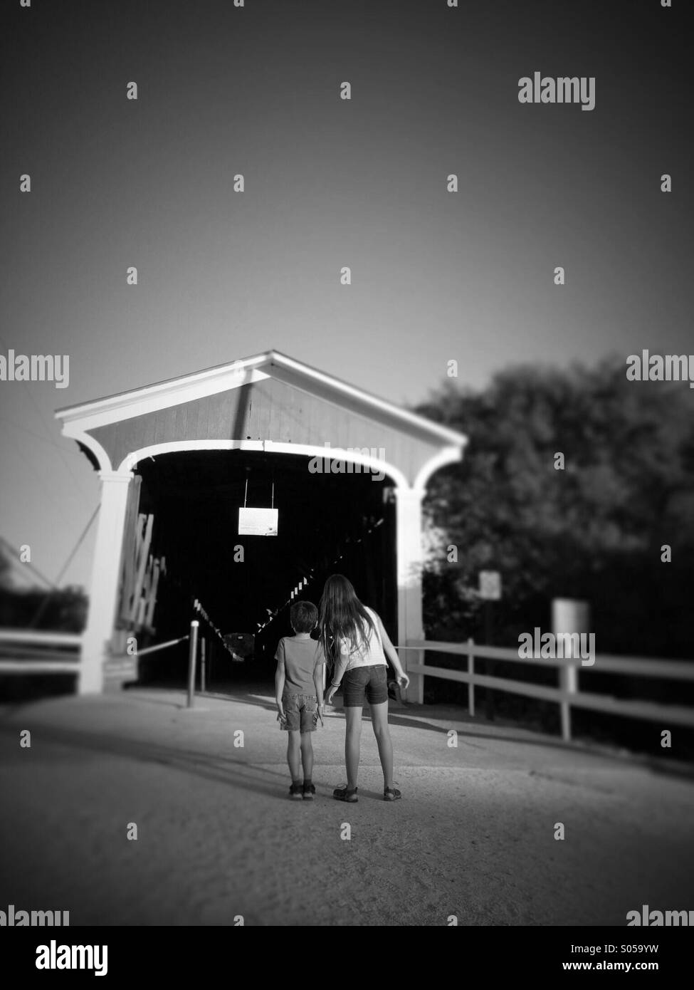 A 10 anno vecchia ragazza e 6 anno vecchio ragazzo guardare in un vecchio ponte coperto. Knights Ferry, CALIFORNIA, STATI UNITI D'AMERICA Foto Stock