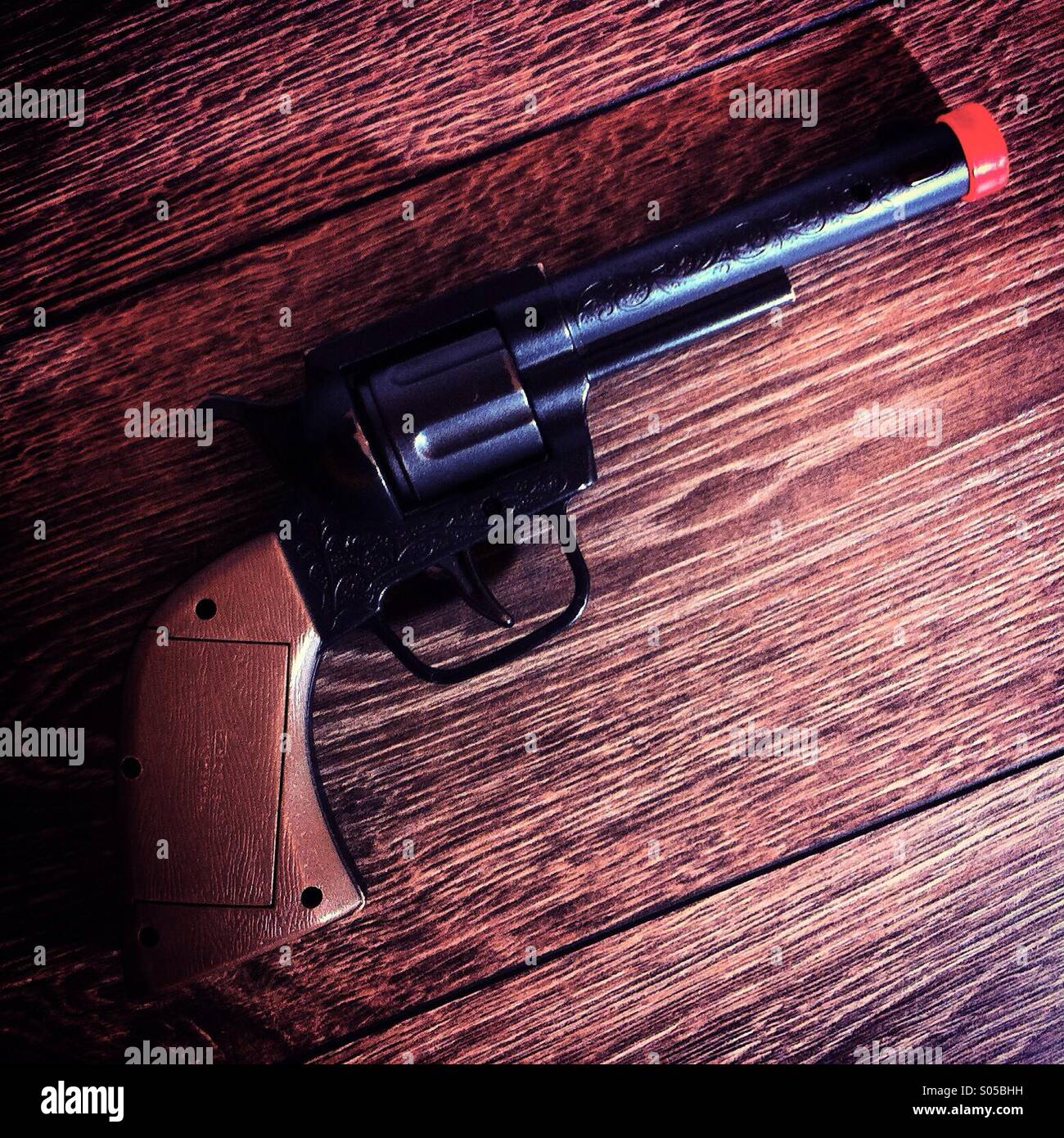 Si tratta di un phpto di un cowboy pistola di plastica giocattolo o pistolet su un wiod sfondo gloor - Immagine stock catturata con smartphone