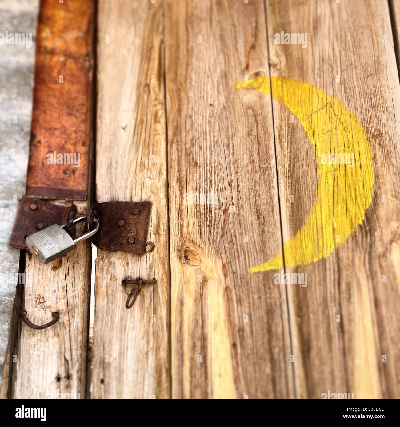 Un giallo di mezza luna dipinta in una porta chiusa con una serratura in Real de Catorce, San Luis Potosi, Messico - Immagine stock catturata con smartphone Un giallo di mezza luna dipinta in una porta chiusa con una serratura in Real de Catorce, San Luis Potosi, Messico - Immagine stock catturata con smartphone