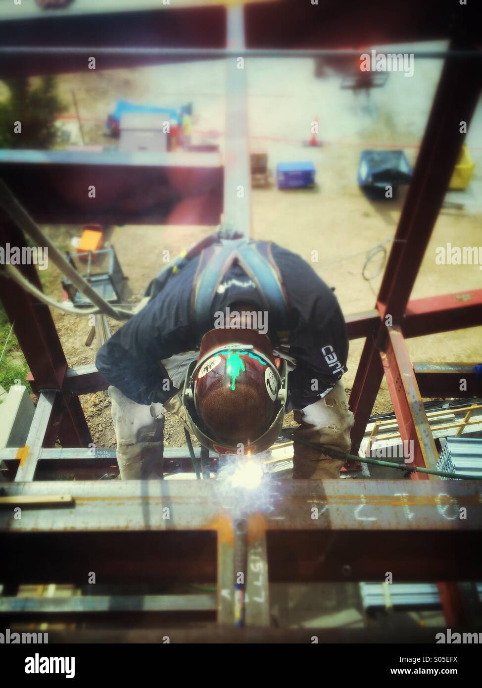 Un lavoratore in acciaio di saldatura di un fascio di luce su un sito di costruzione di un nuovo edificio per uffici - Immagine stock catturata con smartphone