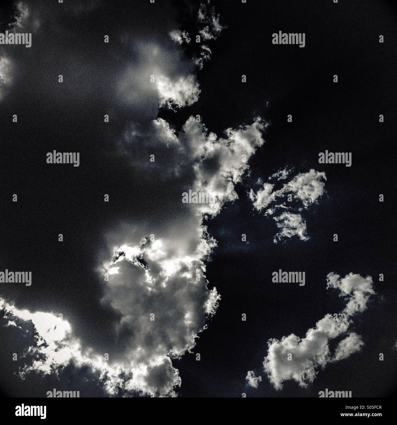 Illuminata da dietro le nuvole in un cielo blu. Foto Stock