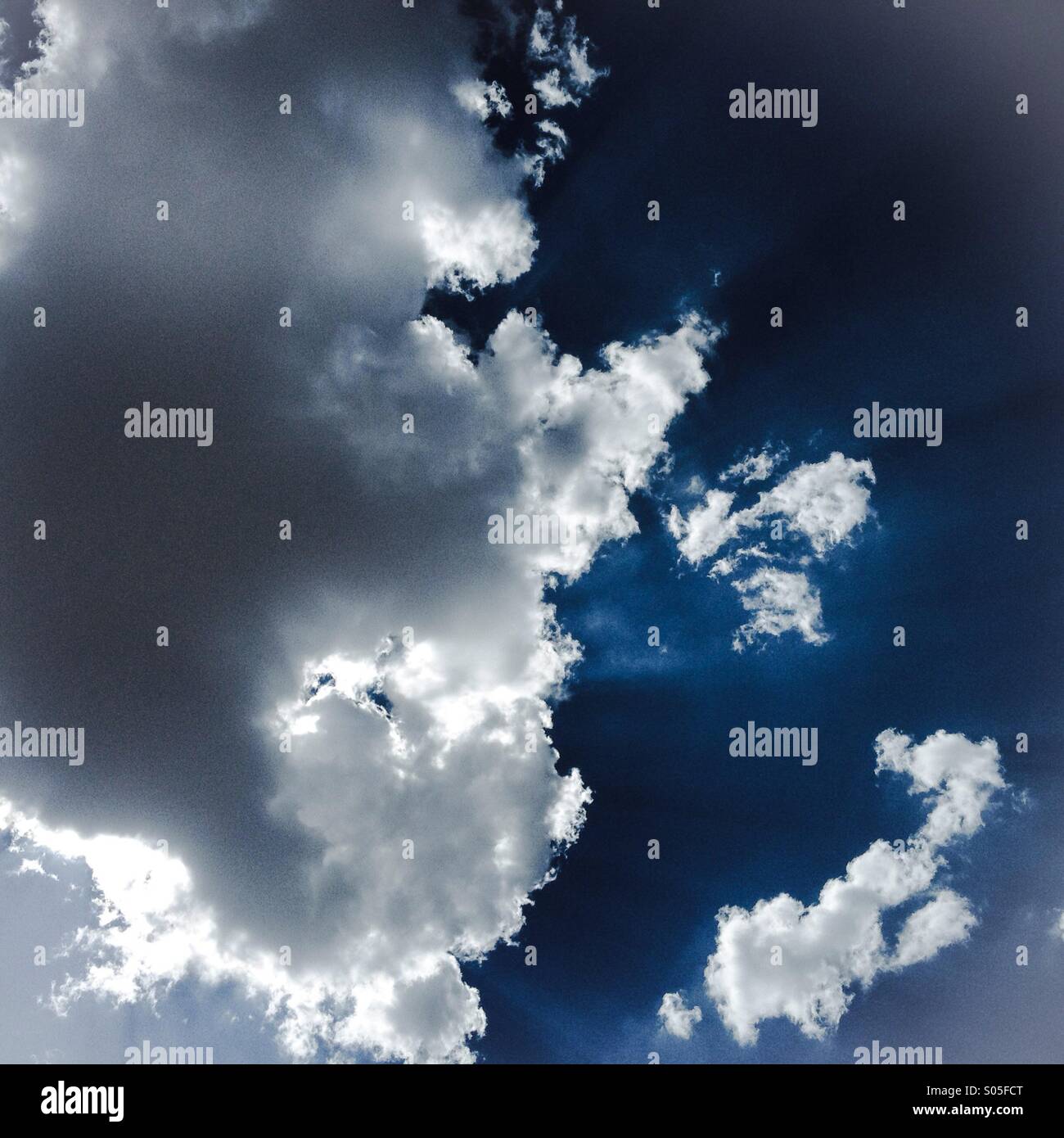 Illuminata da dietro le nuvole in un cielo blu. Foto Stock
