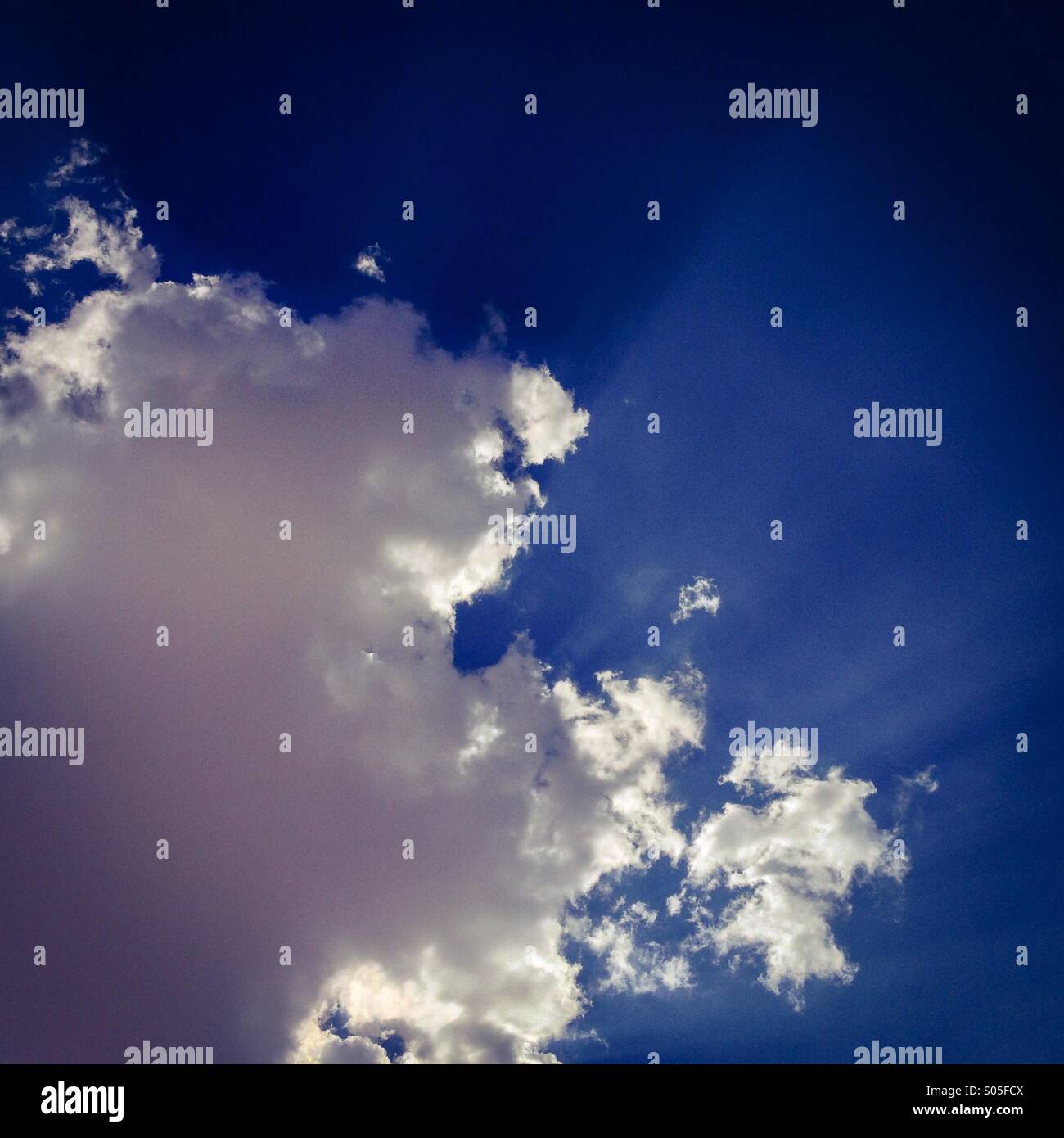 Illuminata da dietro le nuvole in un cielo blu. Foto Stock