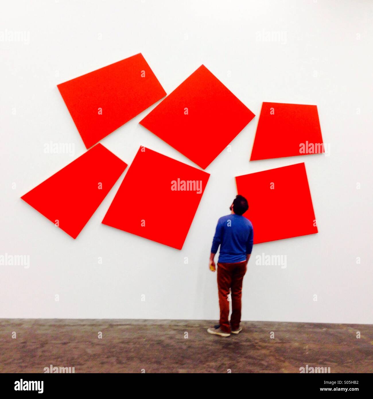 Uomo che guarda all'arte moderna nella galleria d'arte - Immagine stock catturata con smartphone