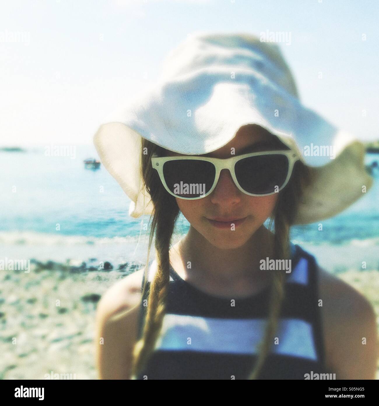 Girl Teen in floppy whit cappello e occhiali da sole sulla spiaggia Foto Stock