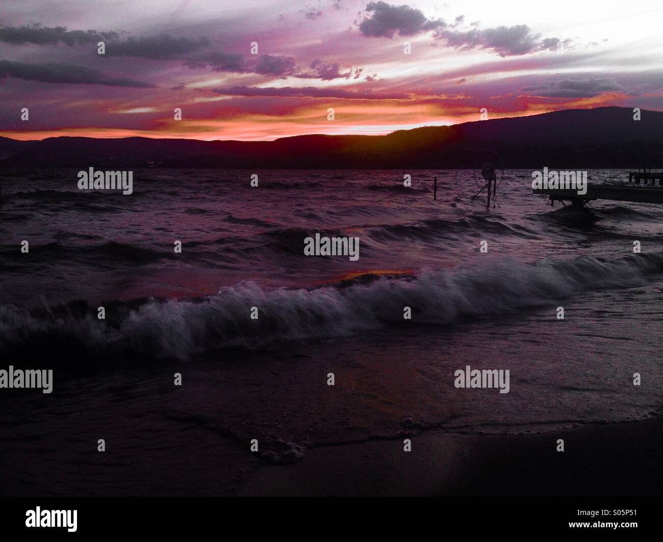 Estate tramonto sul Lago Okanagan. Il sole ha nuotato sotto la montagna, il rosso nel cielo è intensificata da vicino gli incendi boschivi. Foto Stock