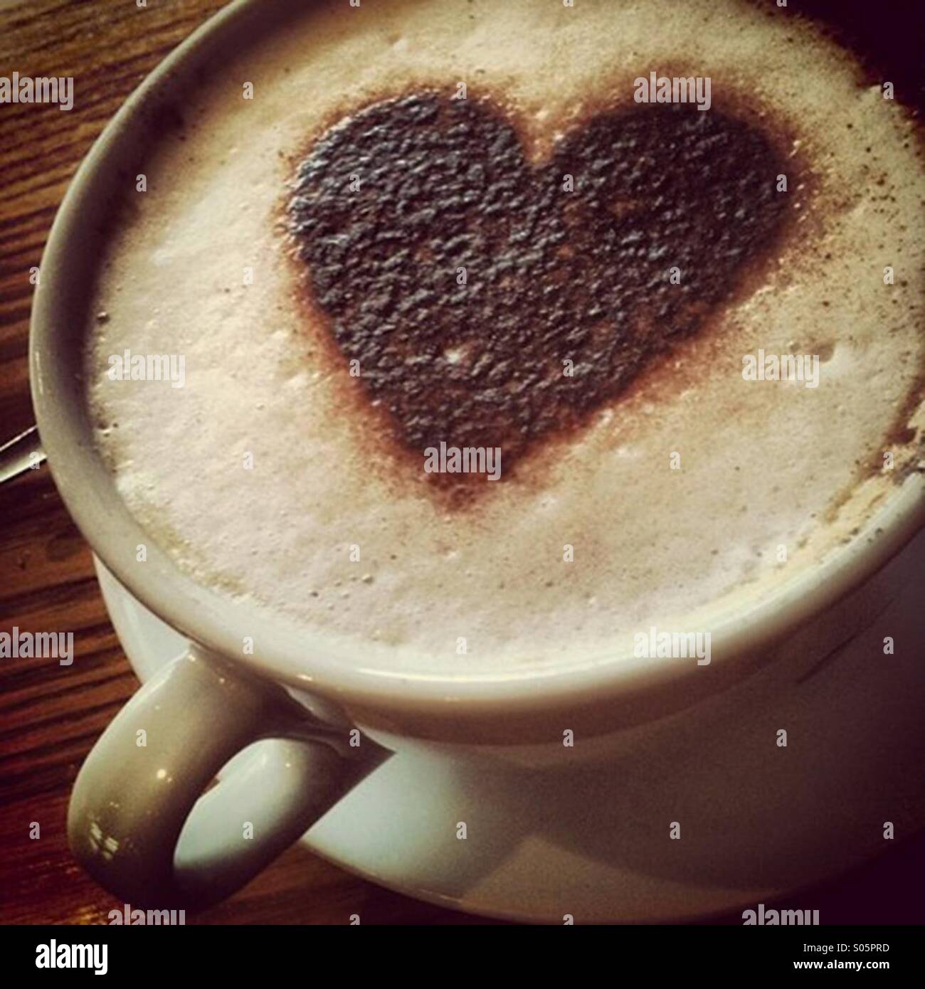Cappuccino bevanda di caffè in tazza grande e un cuore di cioccolato modellato sulla forma la schiuma Foto Stock