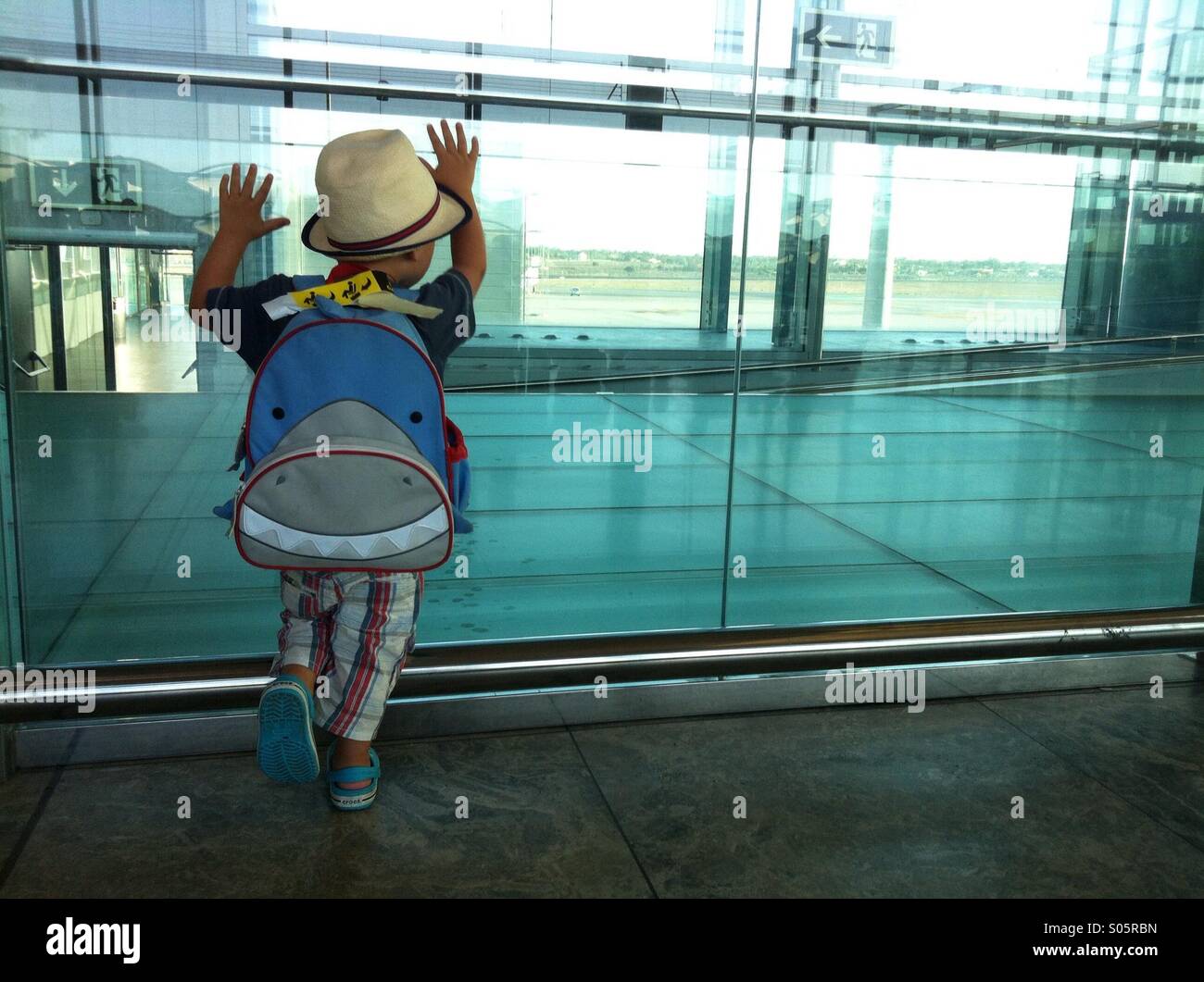 Ragazzo che guarda attraverso una finestra a aeroporto di Alicante Foto Stock