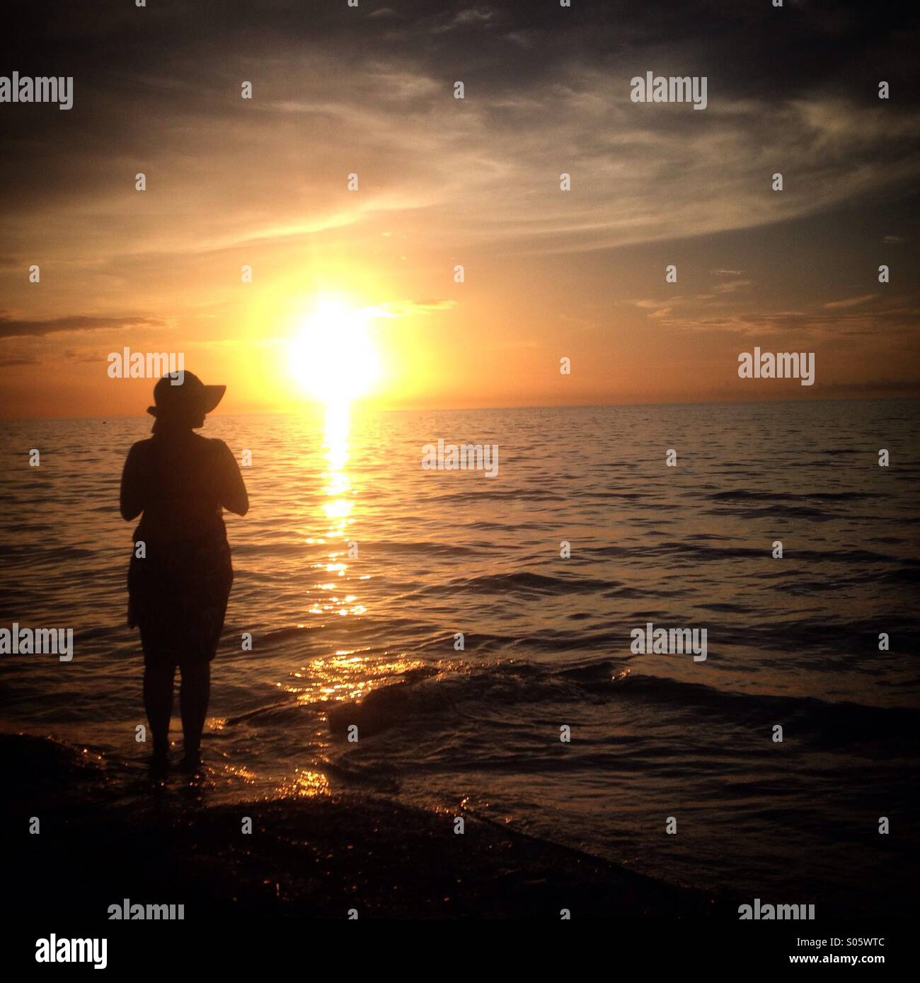 Una donna che indossa un cappello stand al tramonto a Holbox island, Quintana Roo, Messico Foto Stock