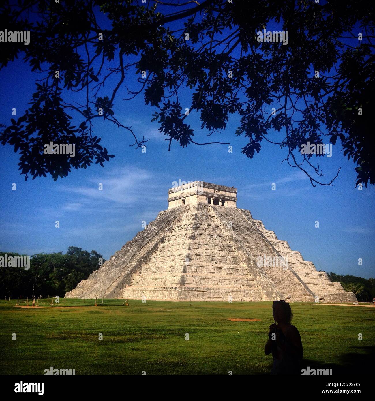 Una donna passa davanti al tempio di Kukulkan nella città Maya di Chichen Itza, Yucatan, Messico Foto Stock