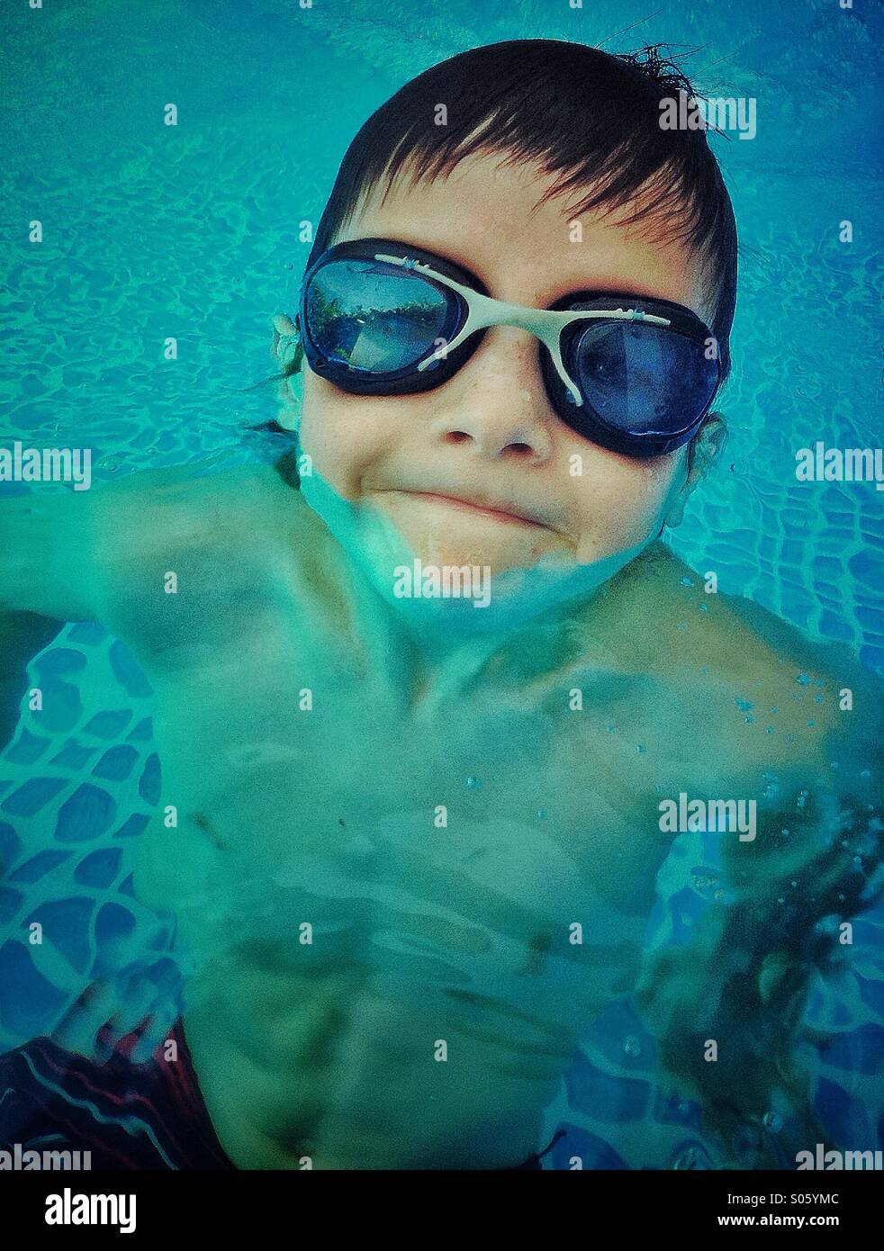 Sorridente ragazzo di giocare e nuotare in un pool Foto Stock