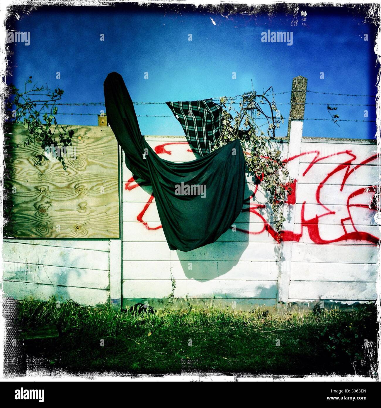 Barriera di cemento muro con graffiti e vecchi su capi di abbigliamento.  Azzurro cielo Foto stock - Alamy