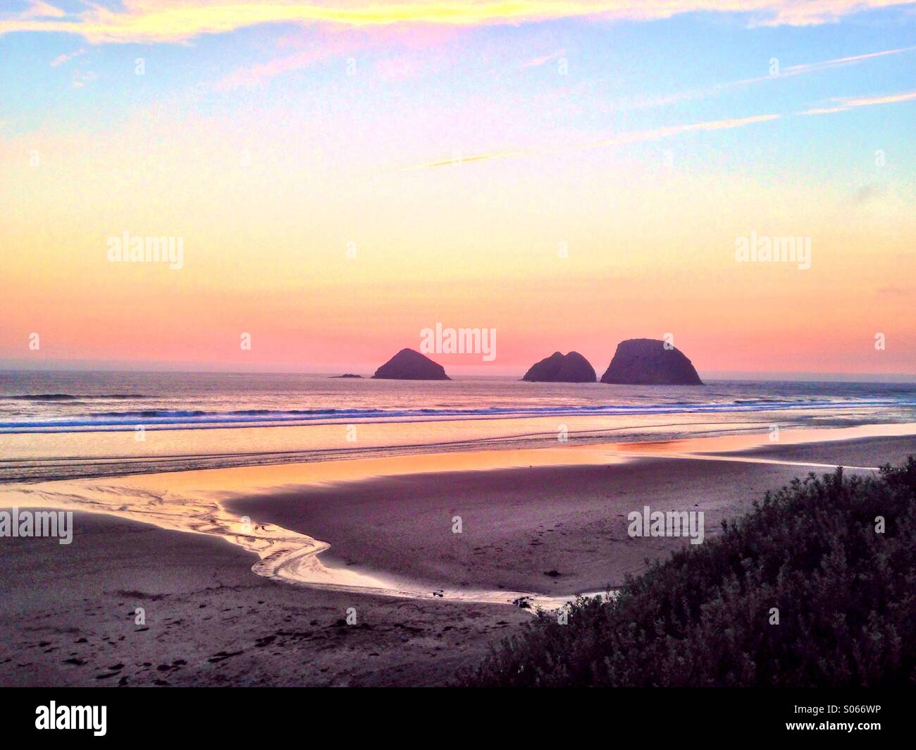 Rocce al largo della costa della Oregon vicino a Cannon Beach si stagliano contro un suggestivo tramonto. Foto Stock