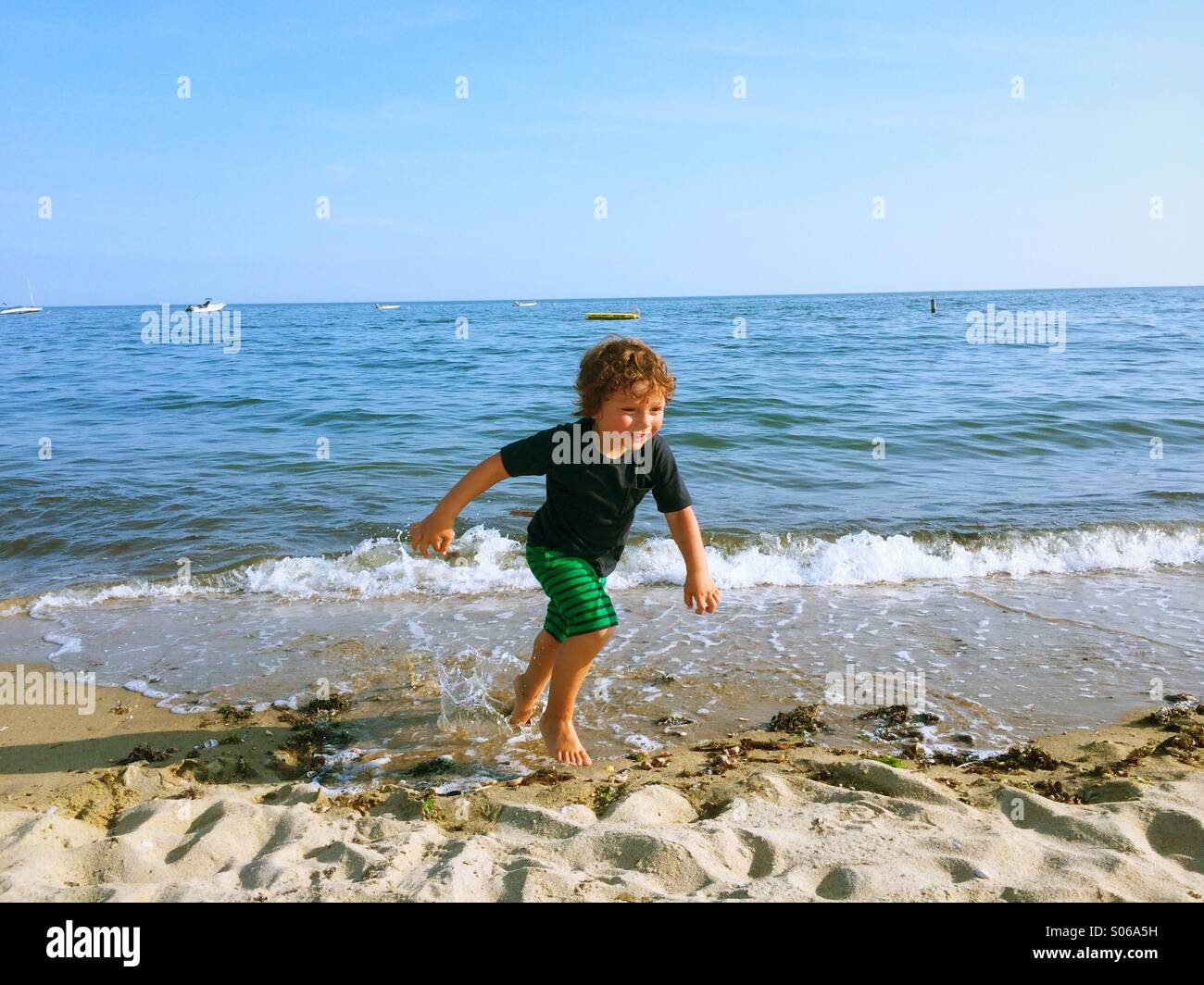 Un piccolo ragazzo giocando su una spiaggia assolata durante l estate in Connecticut, Stati Uniti d'America. Foto Stock