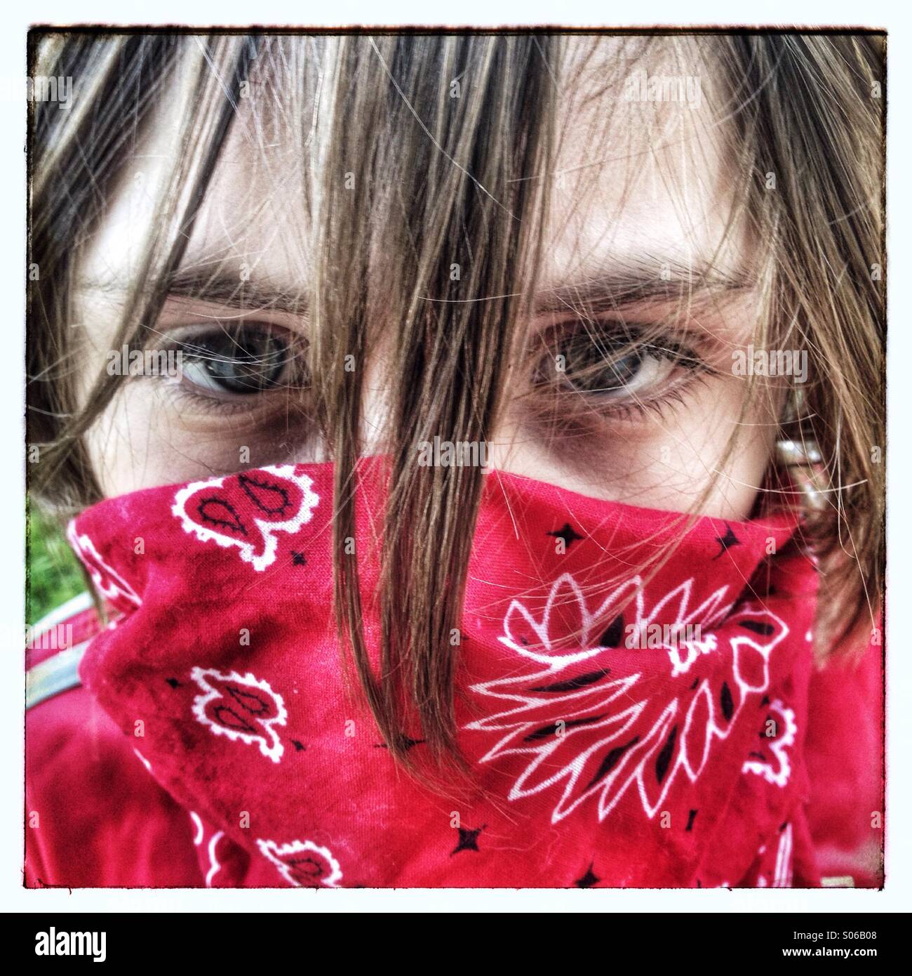 Ragazzo caucasico vestito come un cowboy gunslinger con i capelli lunghi e il fazzoletto rosso. Foto Stock