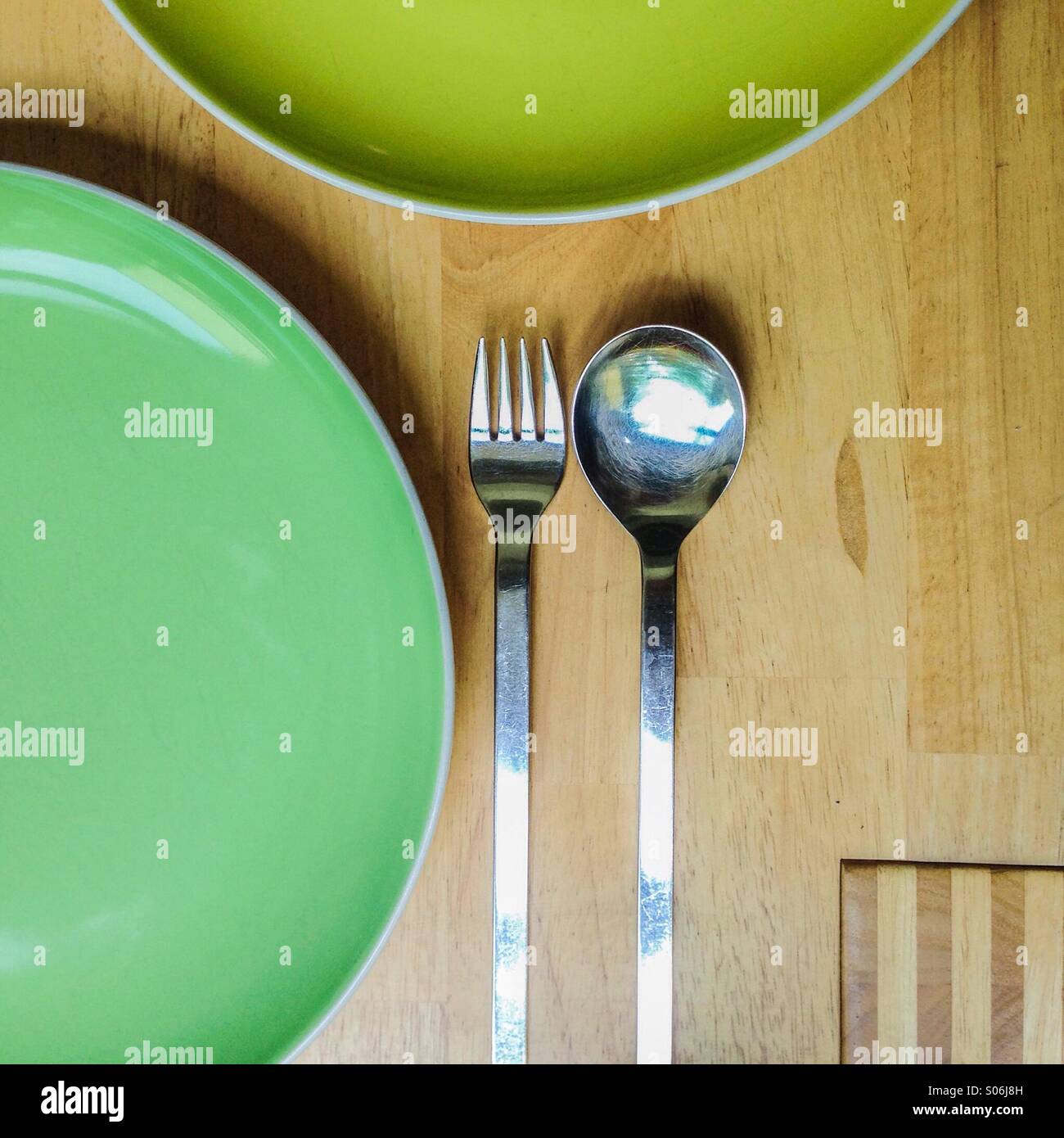 Posateria e stoviglie - piastre, cucchiaio e forchetta sulla tavola di legno Foto Stock