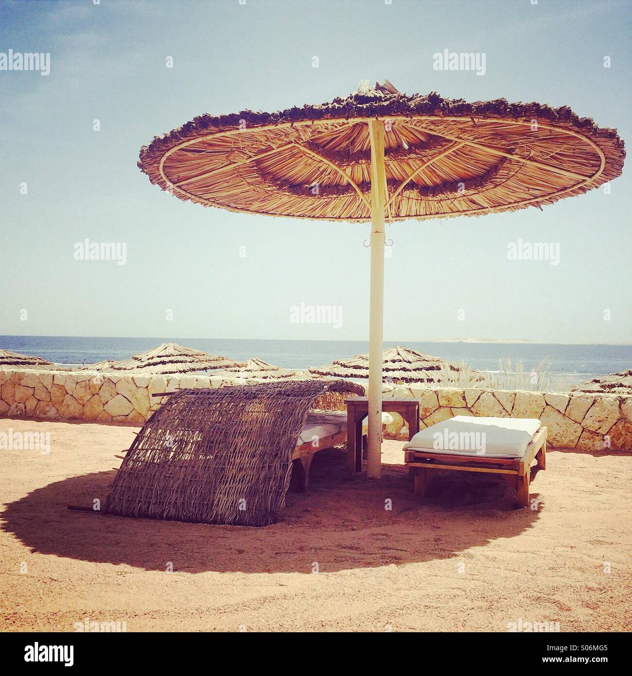 Lettini e ombrellone in una località di villeggiatura in Egitto con un retro filtro applicato - Immagine stock catturata con smartphone