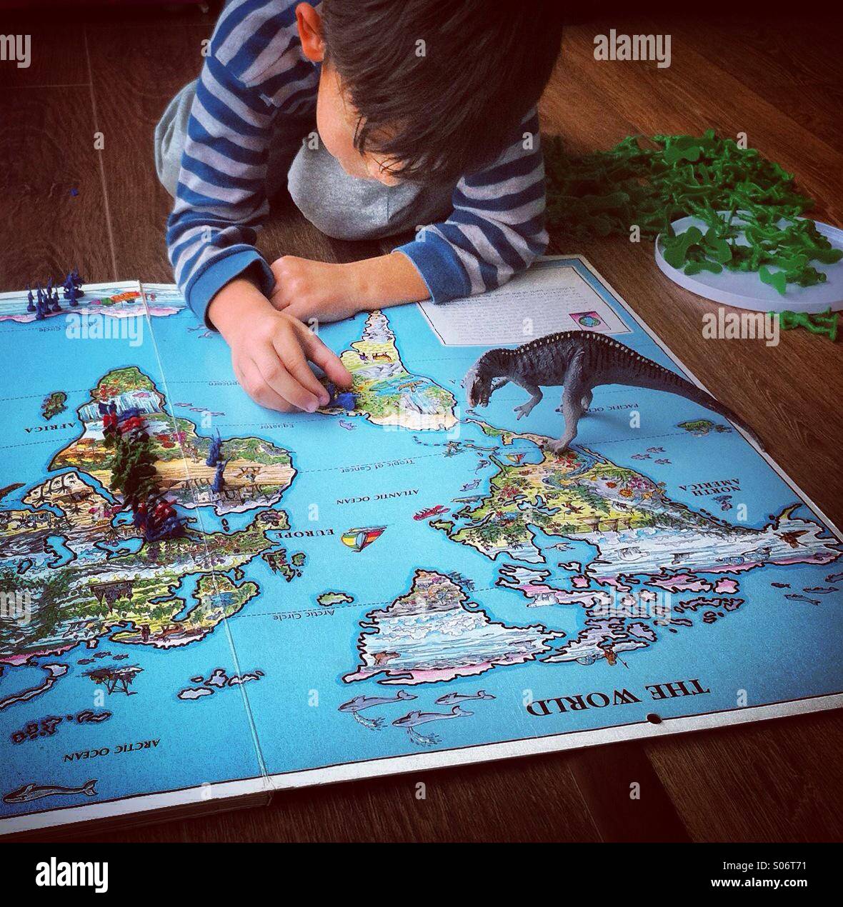 Kid ragazzo giocando dinosaure su una worldmap Foto Stock