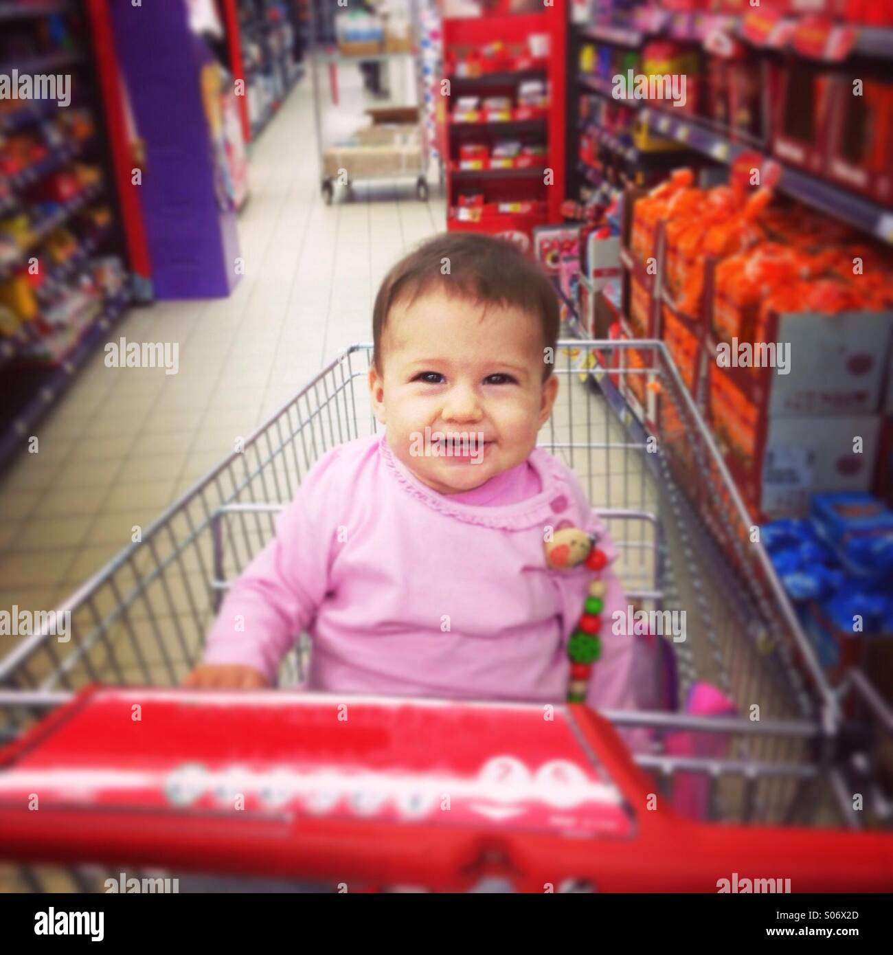 Baby sitter nel carrello di mercato e sorridente Foto Stock