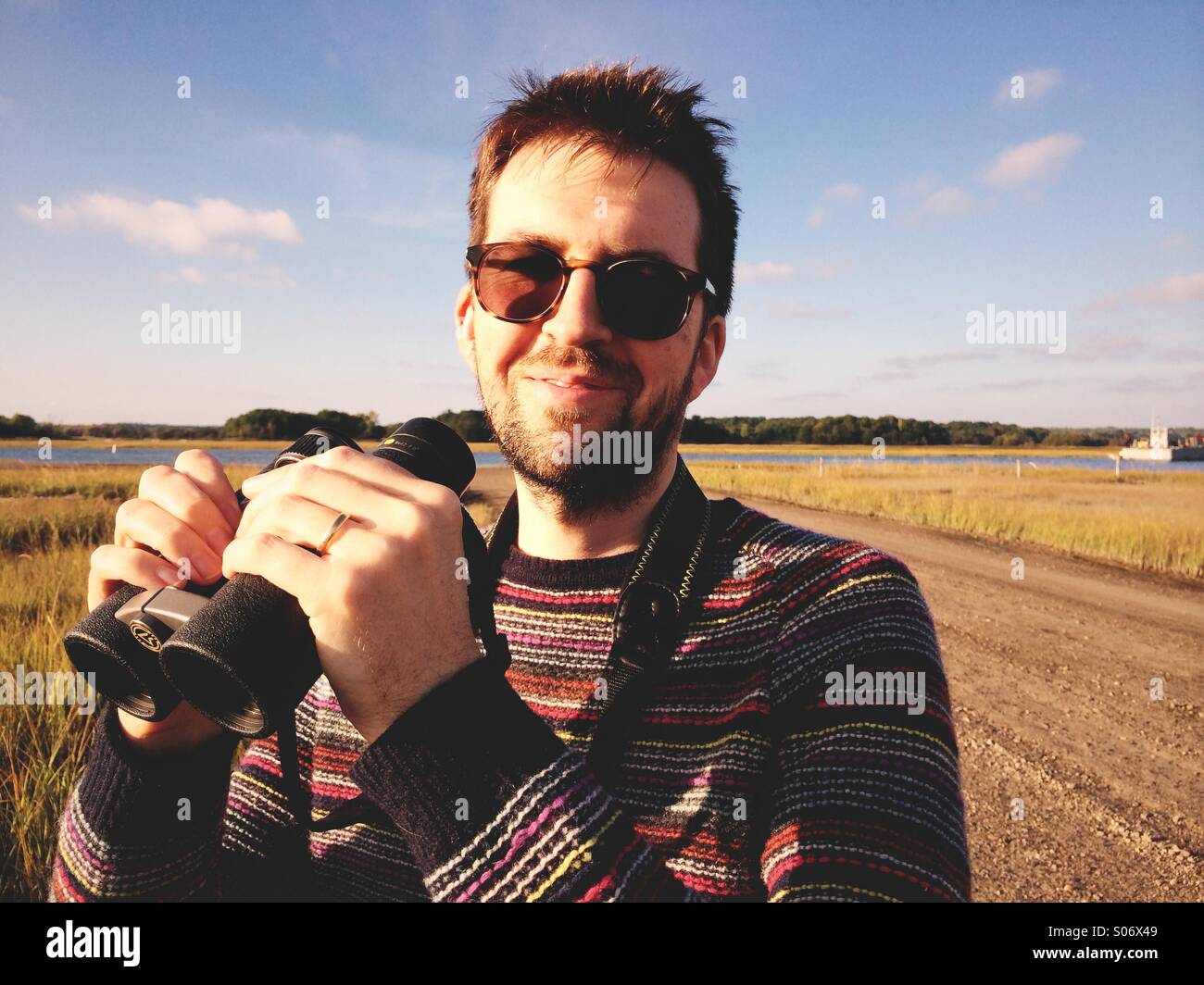 Un giovane uomo con un binocolo birdwatching (o 'birdwatching') sulla costa del Connecticut, Stati Uniti d'America. Foto Stock