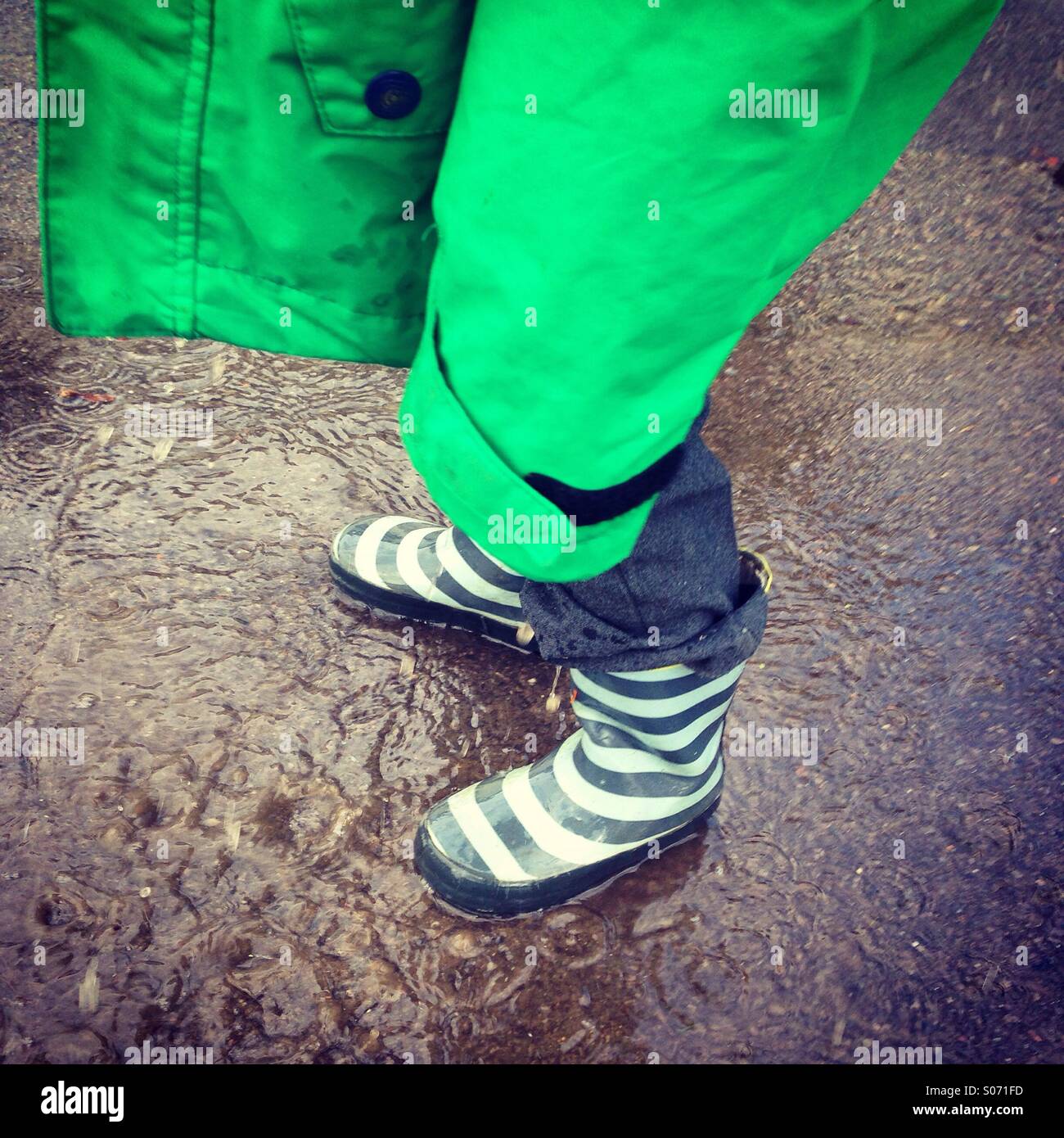 Ragazzo in piedi in una pozza Foto Stock