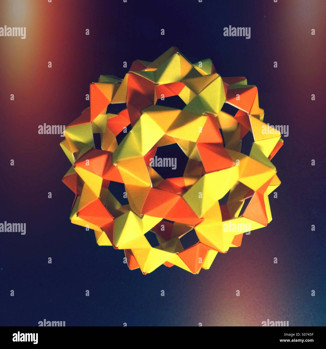 Una sfera di origami in giallo e arancione. - Immagine stock catturata con smartphone