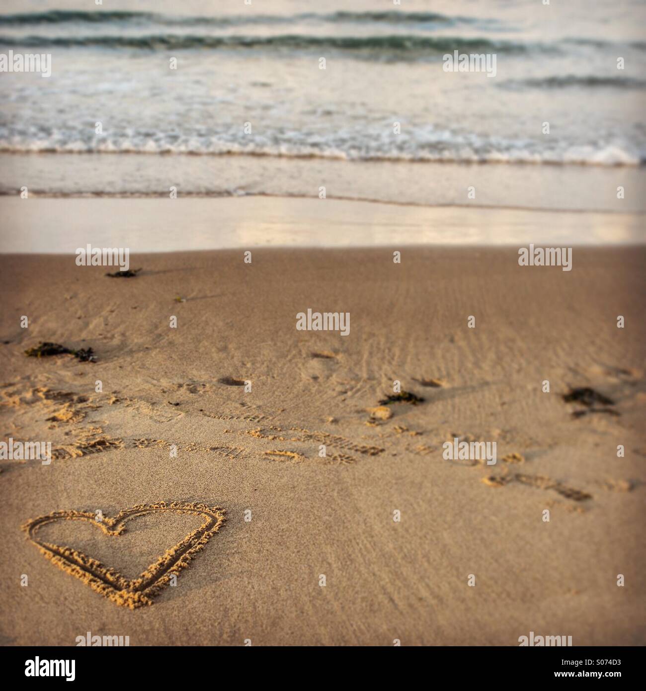 Forma di cuore disegnato nella sabbia in spiaggia - Immagine stock catturata con smartphone