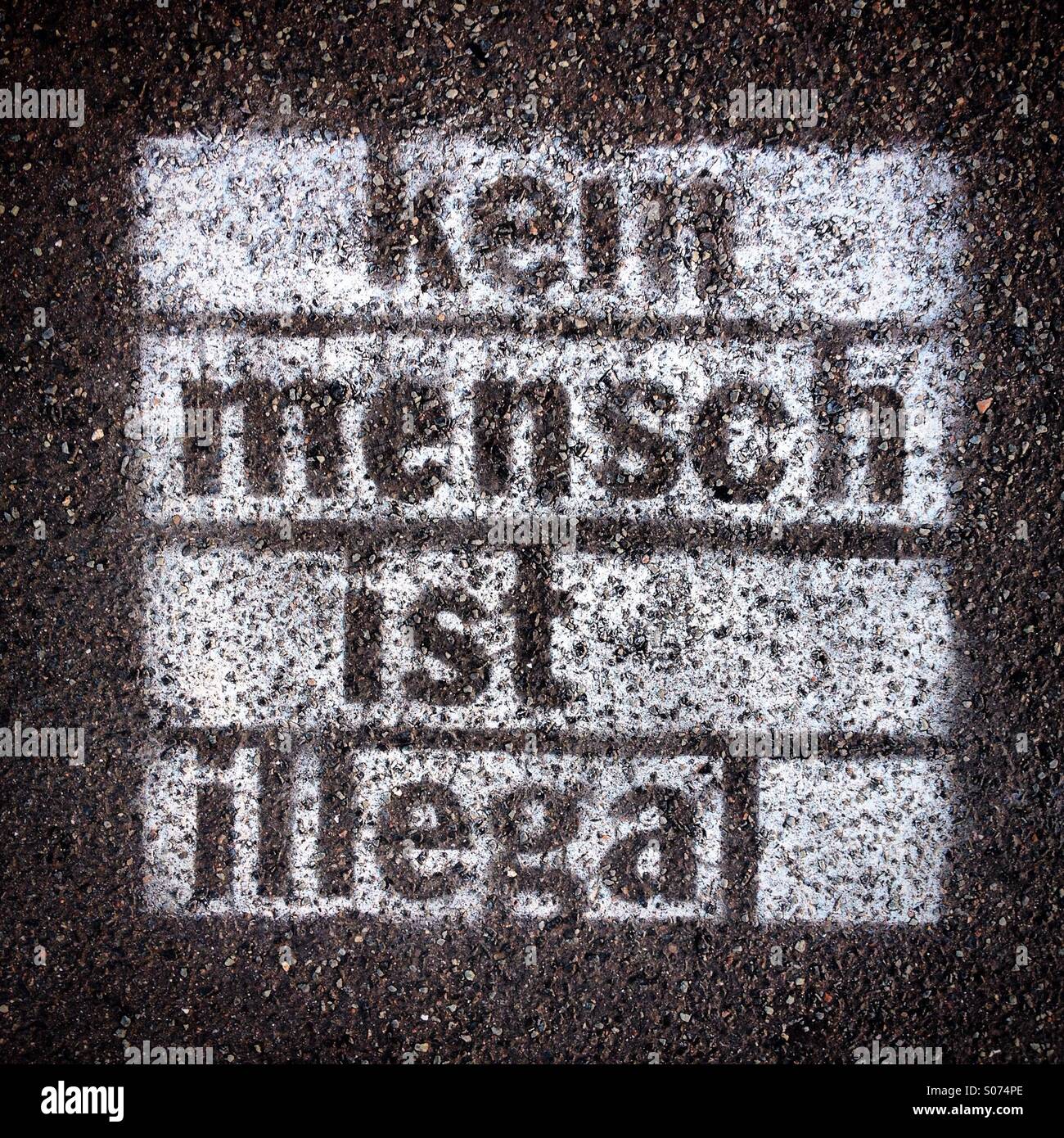 Verniciato a spruzzo graffiti sul marciapiede con parole "Kein Mensch ist illegale" scritta in tedesco (nessuna persona è illegale) Foto Stock