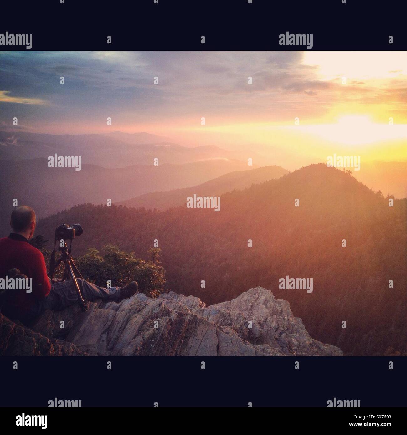 Un fotografo si siede con la sua macchina fotografica e guardato un bel tramonto sviluppare oltre lo Smoky mountains Foto Stock