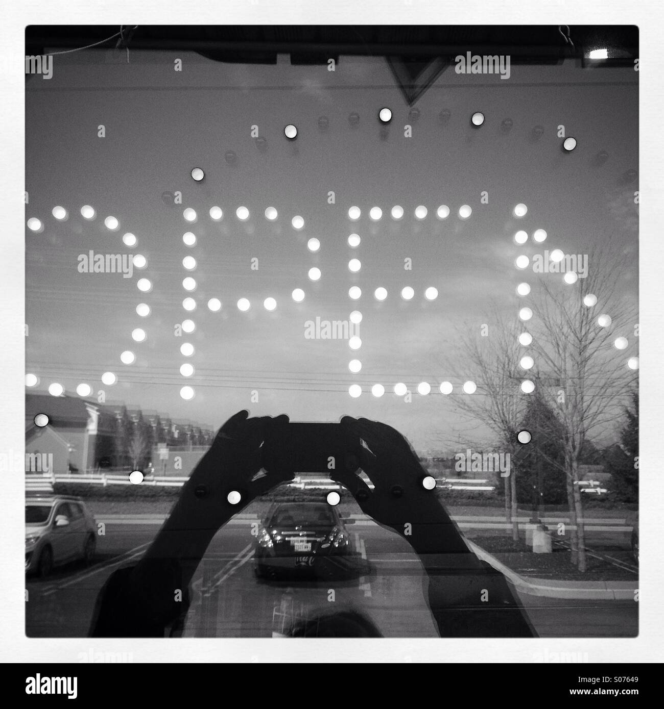 Aprire per il segno aziendale. Selfie. In bianco e nero la riflessione nella vetrina di un negozio. Foto Stock