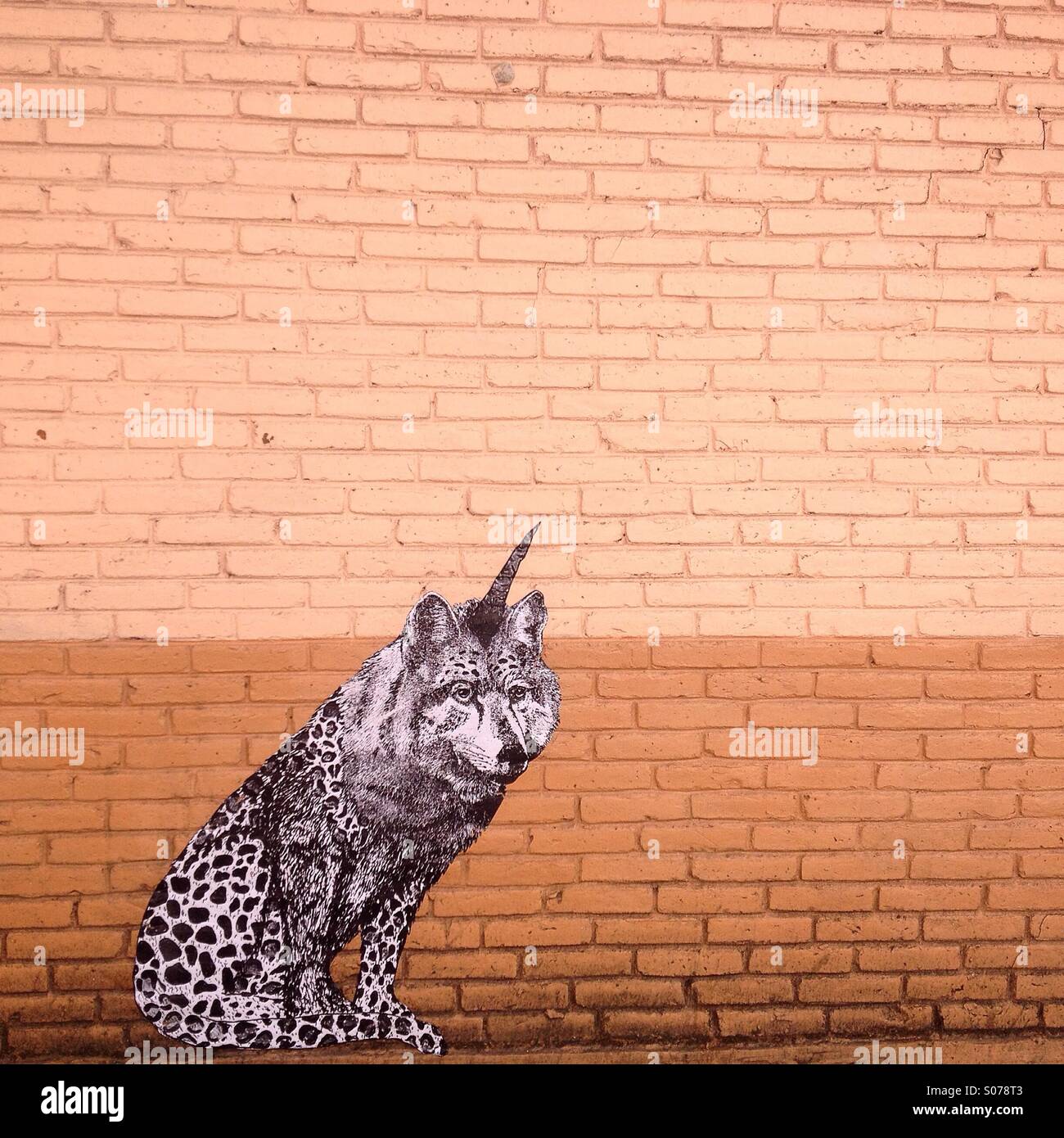 Un animale fantastico, mix di una Jaguar, un lupo e un unicorno, decora un arancio muro in mattoni a Colonia Roma, Città del Messico, Messico Foto Stock