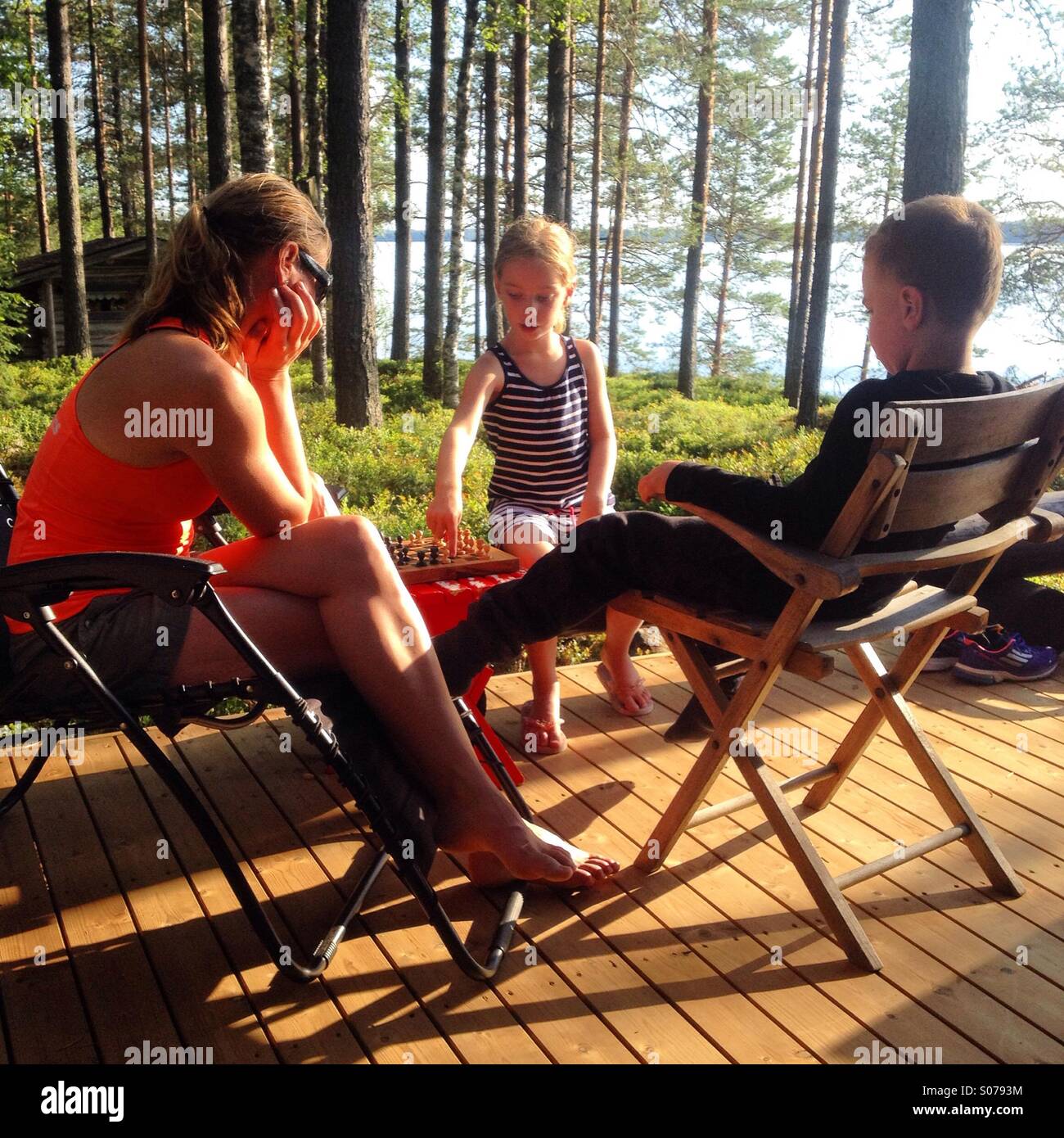 Una famiglia giocando a scacchi insieme su un Nordic summerhouse vacanze nel nord della Finlandia Foto Stock