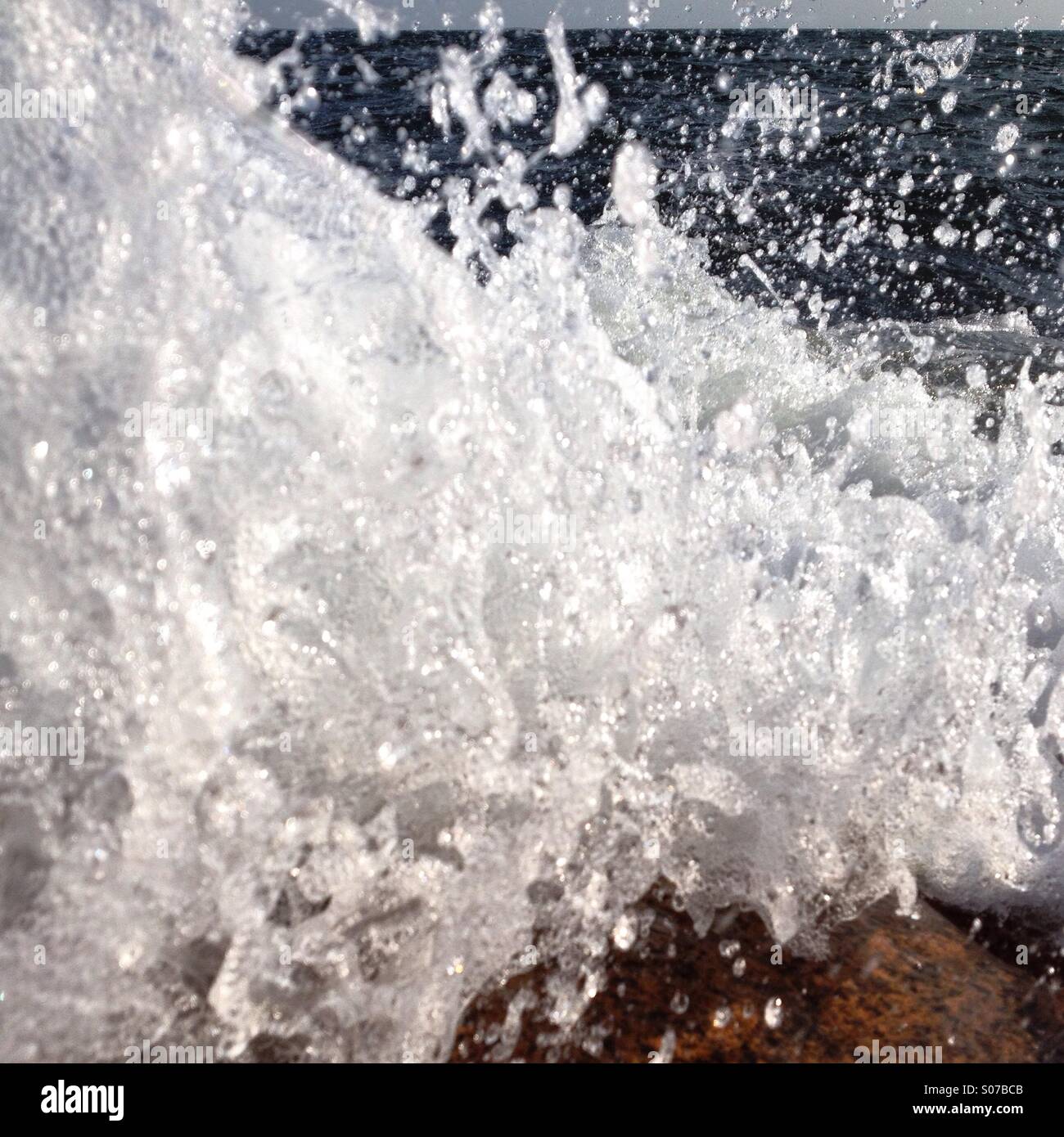 Un'onda rottura sulle rocce catturato all'ultimo momento prima che colpisce la lente - Immagine stock catturata con smartphone