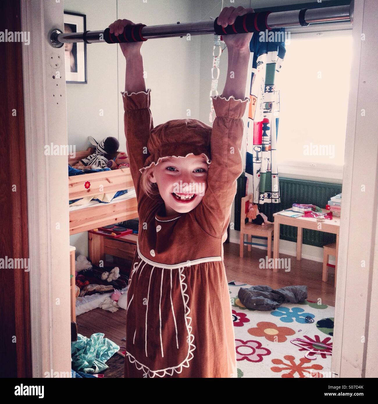 Una ragazza in costume e sorridente basculante in una ginnastica bar attraverso la porta della sua camera da letto a casa Foto Stock