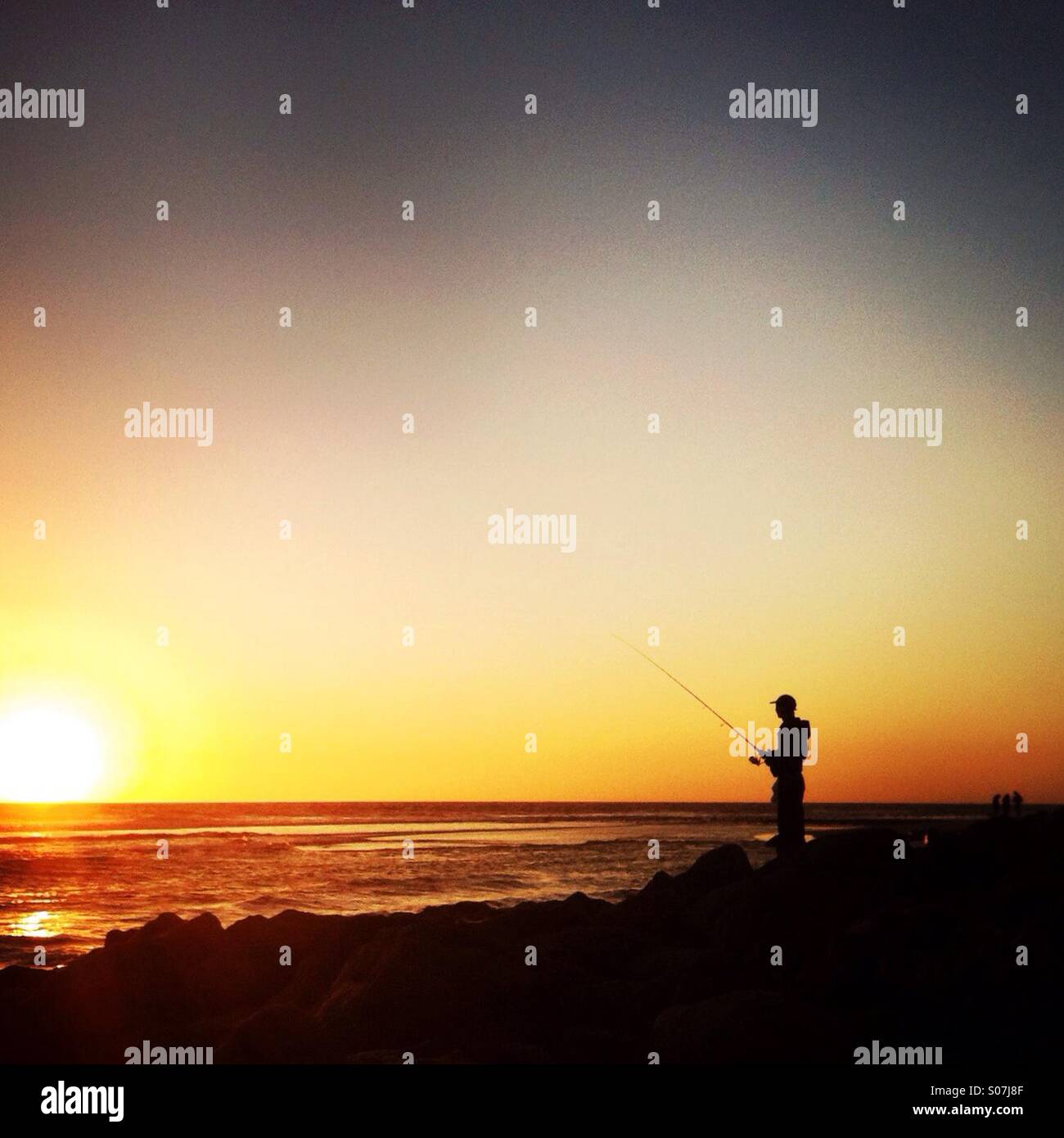 Una silhouette di un uomo la pesca in spiaggia. Ventura, California USA. Foto Stock