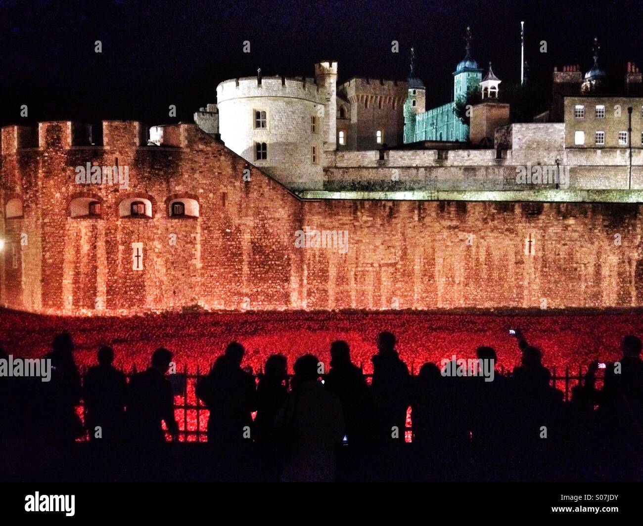 Le persone si radunano di notte per vedere installazione artistica " sangue spazzata di terre e mari del rosso, che consiste di 888,246 ceramica rosso papavero piantato nel fossato presso la Torre di Londra. - Immagine stock catturata con smartphone