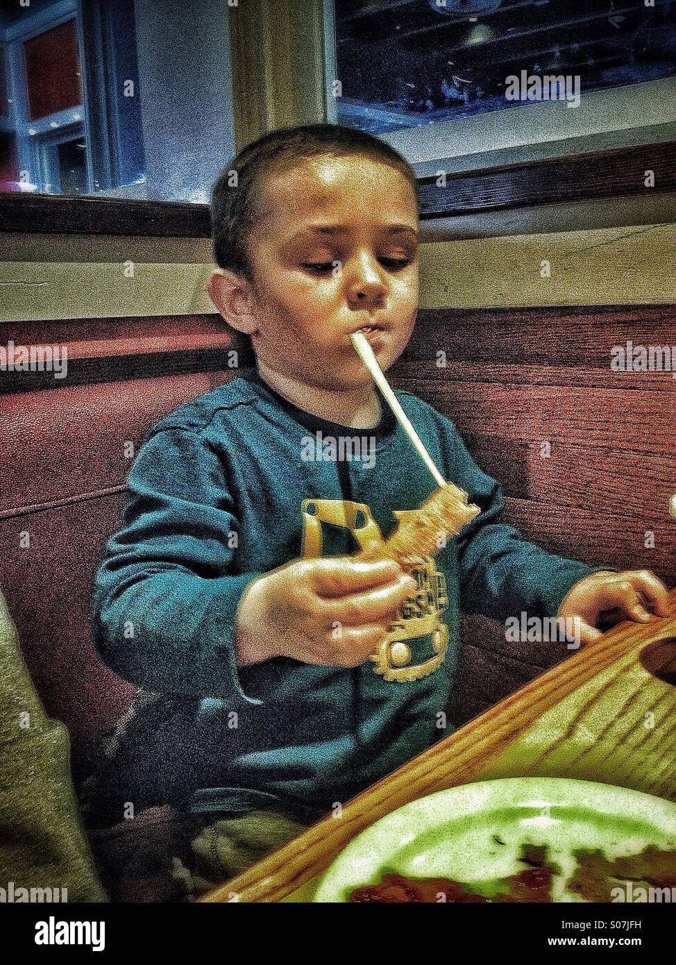 Buon formaggio! 4 anno vecchio ragazzo con una lunga stringa di formaggio dalla bocca a mano. HDR Foto Stock