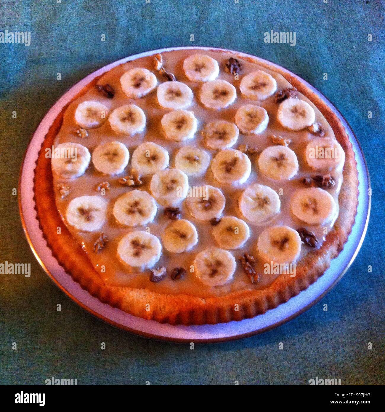 Torta Banoffee - deliziosa torta alla banana fatta in casa con crosta dorata e un ricco ripieno servito su un semplice tavolo blu - Immagine stock catturata con smartphone