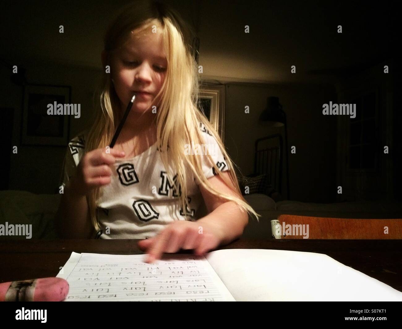 Una giovane ragazza sta facendo il suo dovere e leggere le lettere che lei ha scritto nel suo libro scolastico. Foto Stock