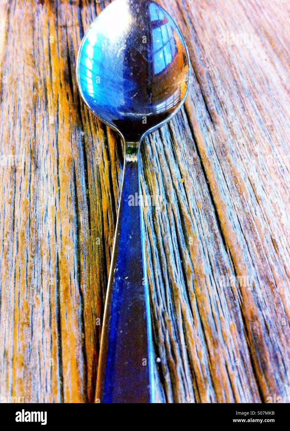 Un cucchiaio di lucido su un vecchio tavolo in legno Foto Stock