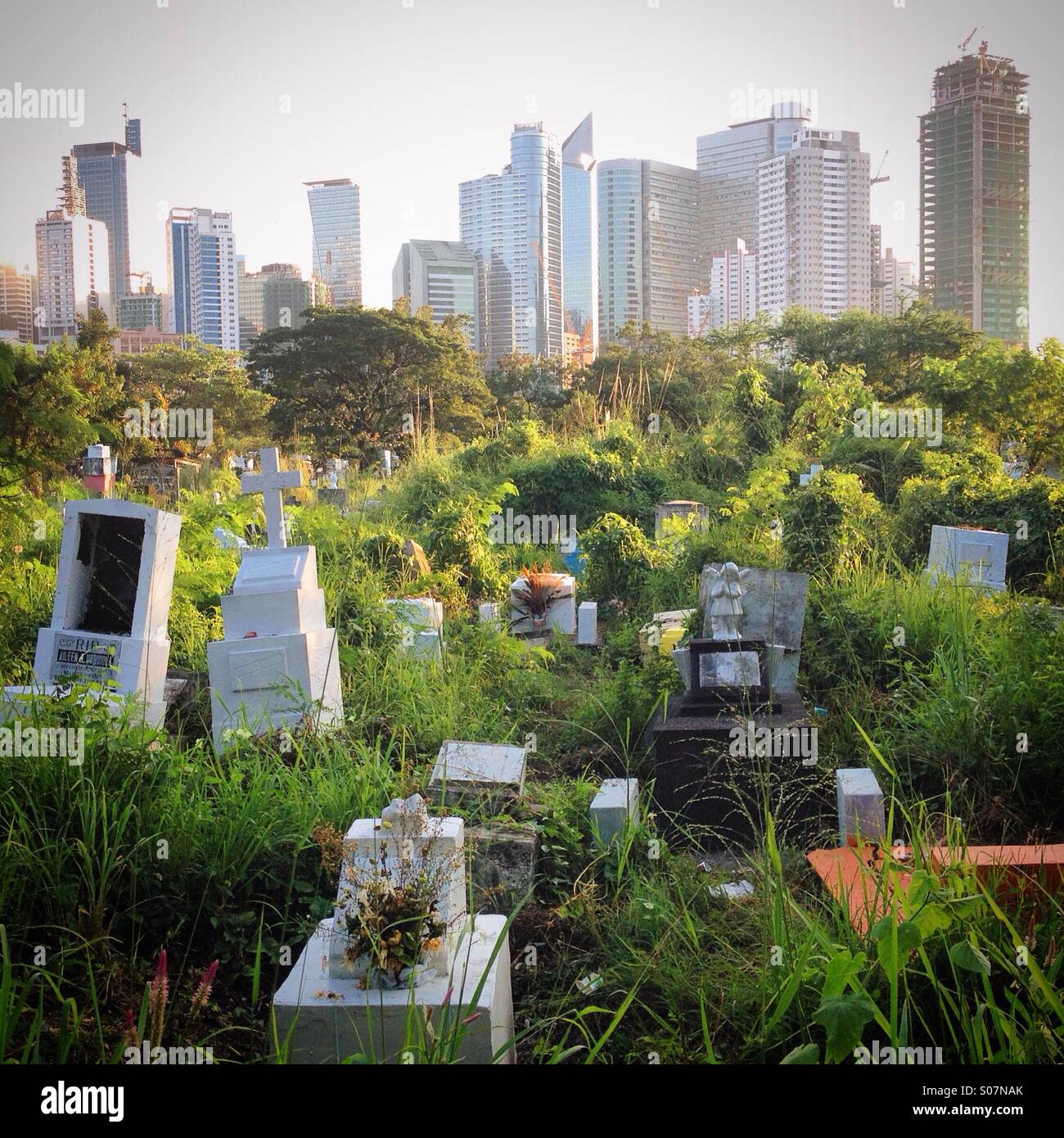 Le tombe dei poveri sprofondare nella palude di Manila Sud cimitero come le torri di Makati business district salire dietro a pochi isolati di distanza. Makati Manila, Filippine Foto Stock