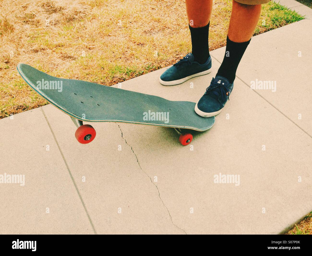 Uomo con calzini, scarpe da ginnastica e uno skateboard su un marciapiede  Foto stock - Alamy