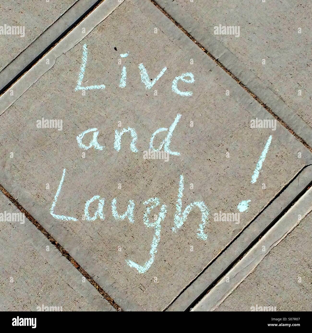 Vivere e ridere scritti in gesso sul marciapiede Foto Stock