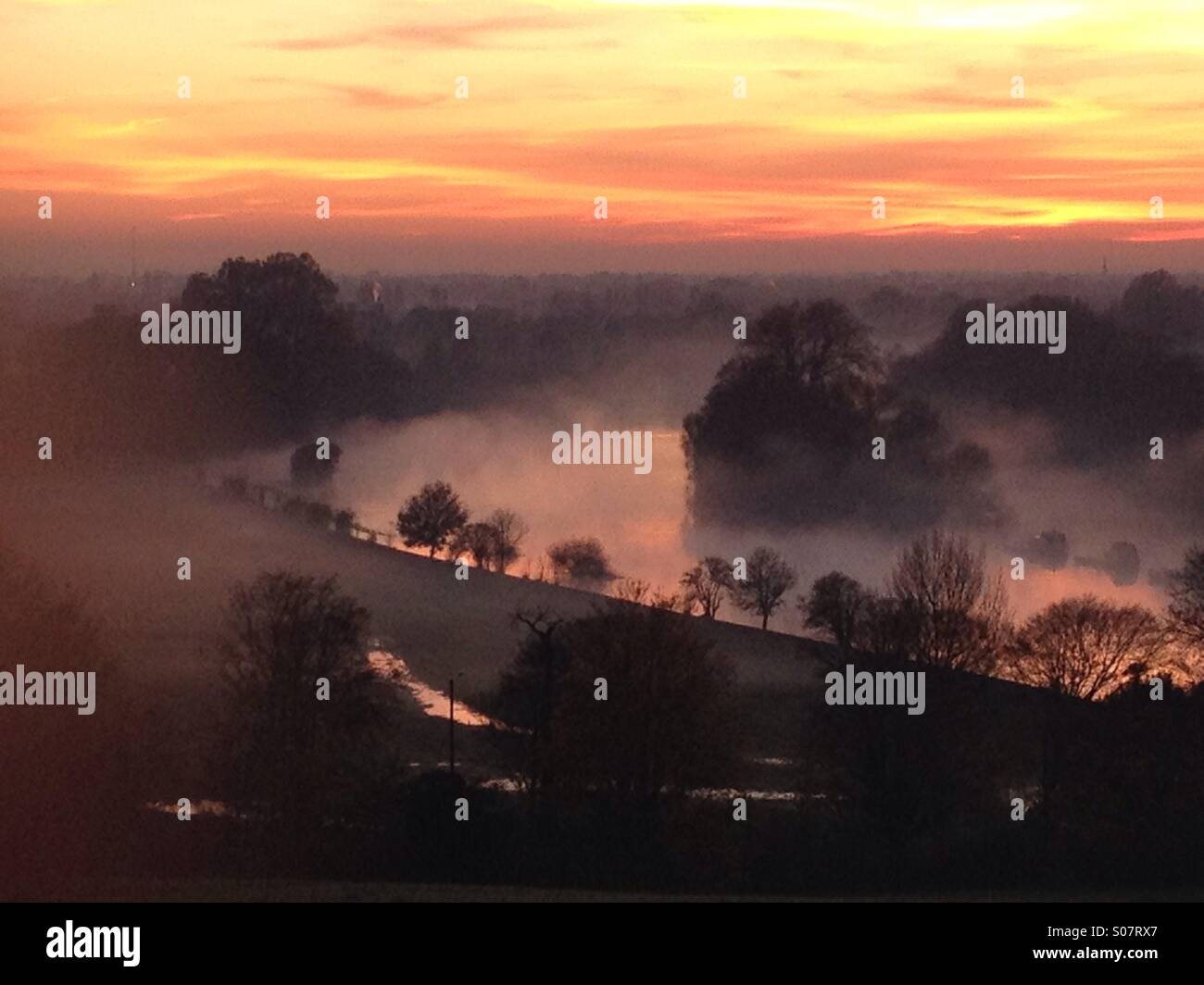 La vista sul fiume Tamigi da Richmond Hill, Surrey, al tramonto in una nebbiosa nebbiosa serata autunnale nel mese di novembre. Lo sbiadimento della luce del sole illumina la nebbia. - Immagine stock catturata con smartphone