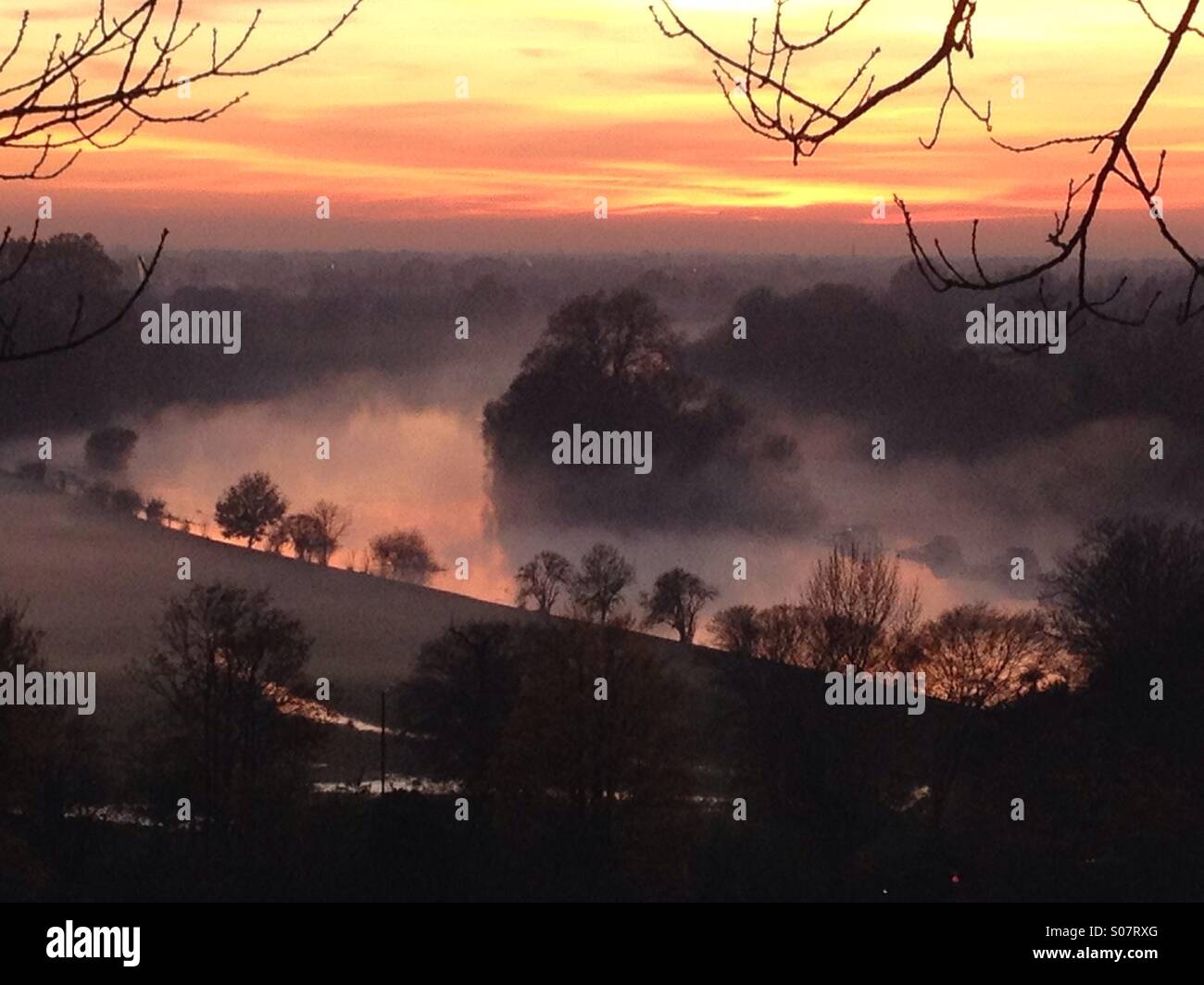 La vista sul fiume Tamigi da Richmond Hill, Surrey, al tramonto in una nebbiosa nebbiosa serata autunnale nel mese di novembre. Lo sbiadimento della luce del sole illumina la nebbia. - Immagine stock catturata con smartphone