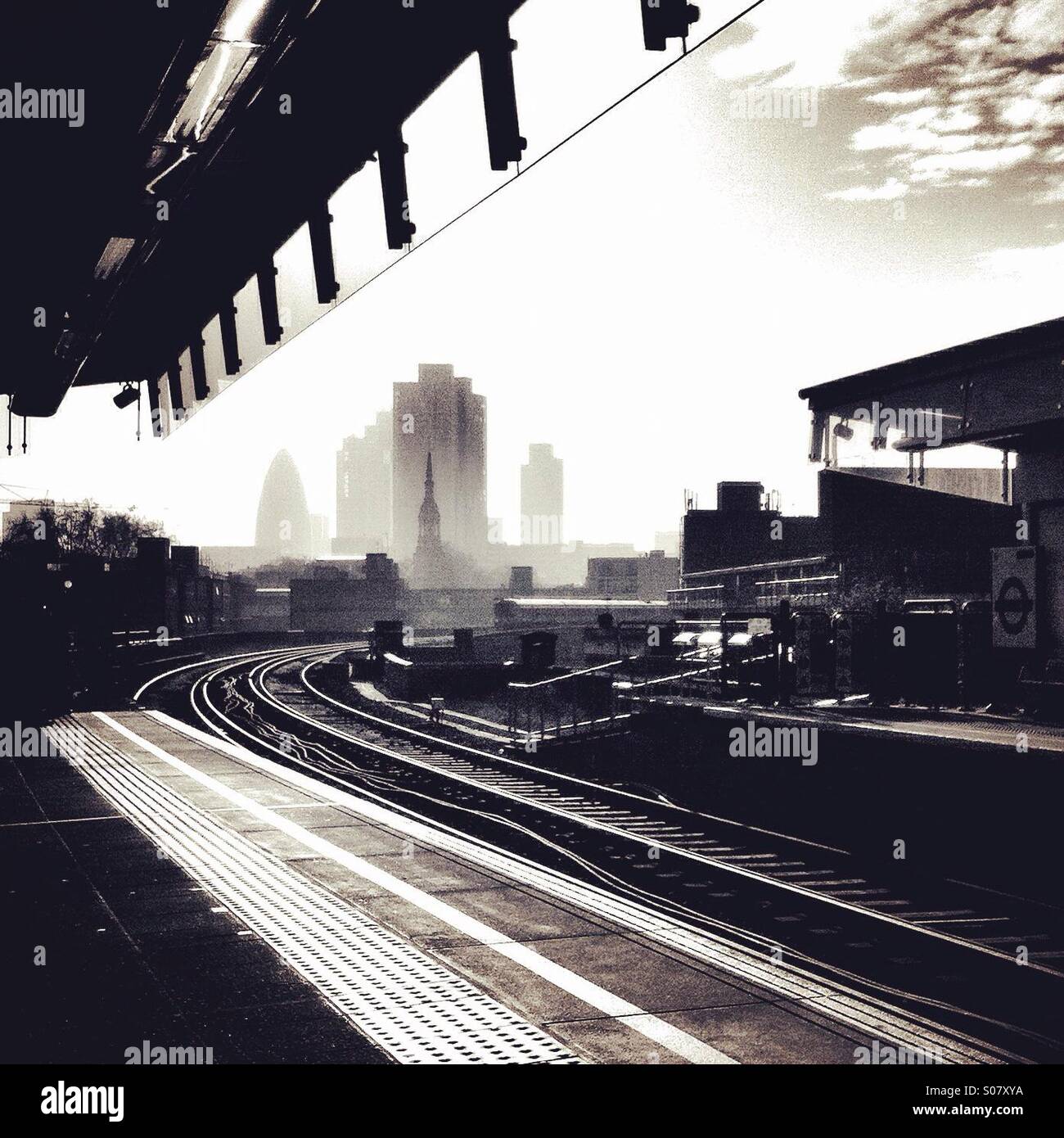 Grattacieli nella città di Londra si vede nella distanza, dal punto di vista della piattaforma a Hoxton overground stazione su una leggermente torbida giorno, in bianco e nero Foto Stock