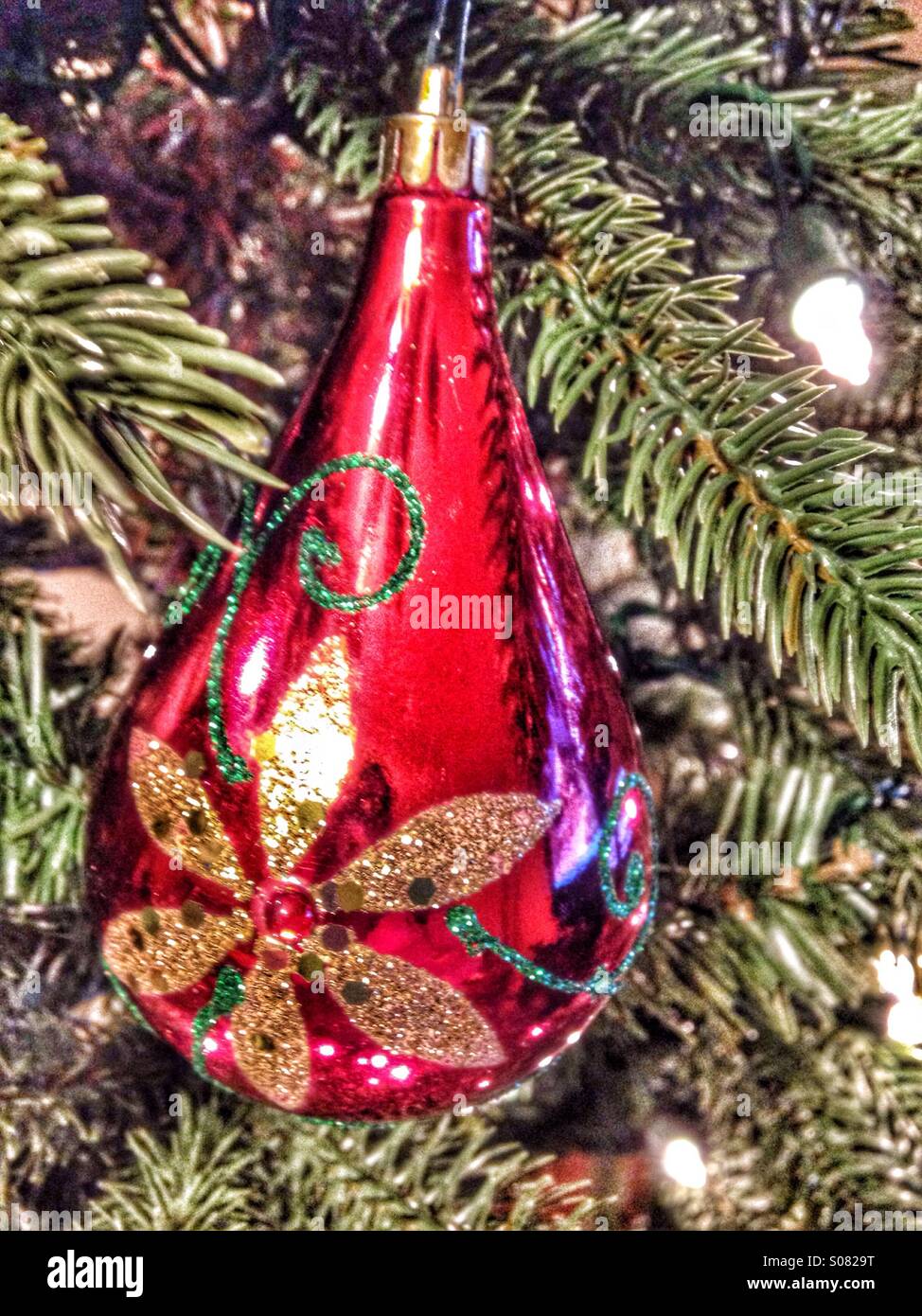 Un rosso a forma di lacrima ornamento appeso a un albero di Natale. - Immagine stock catturata con smartphone